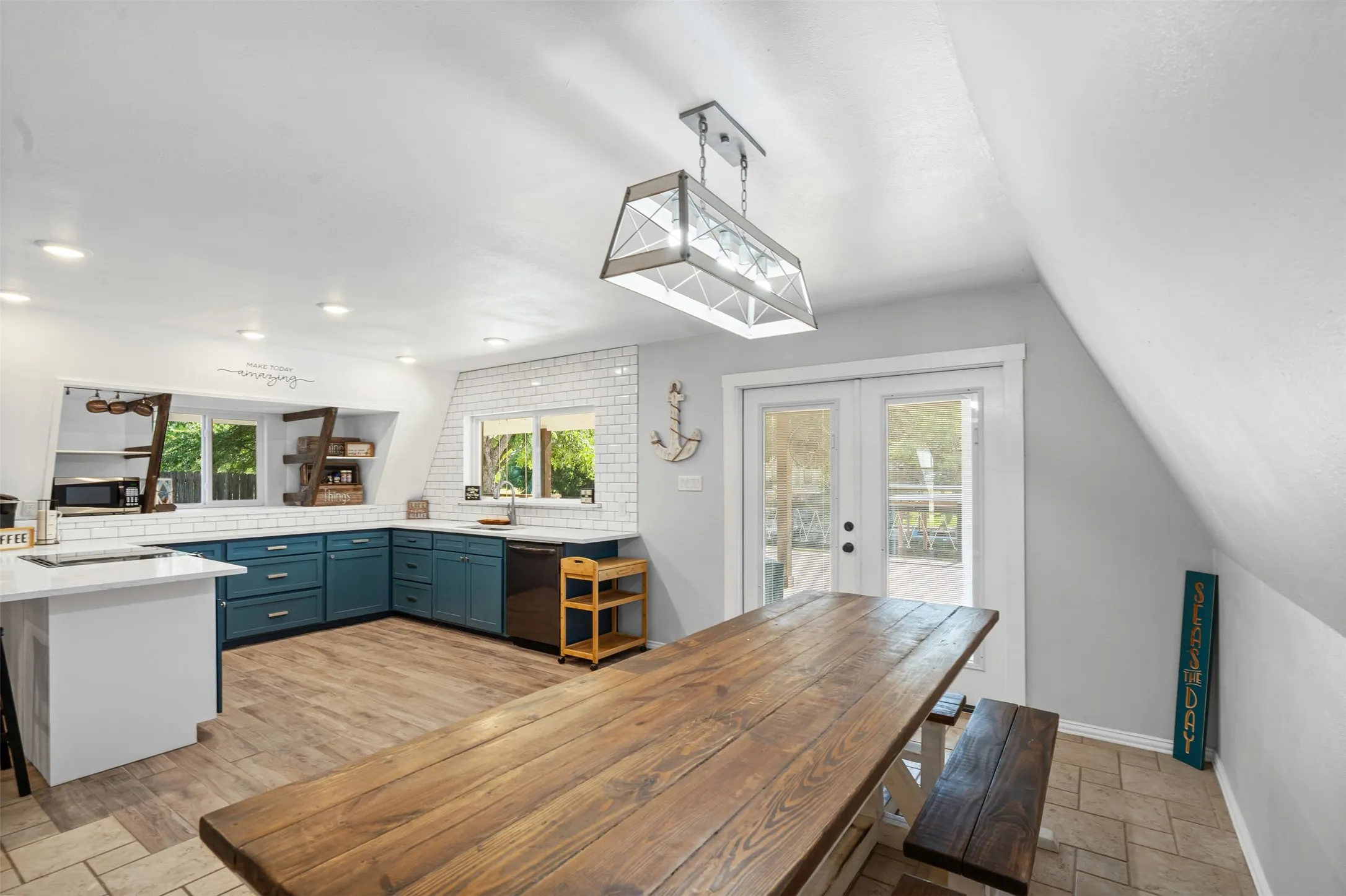 Kitchen with french doors, stone tile flooring, blue cabinetry, a kitchen breakfast bar, and a peninsula