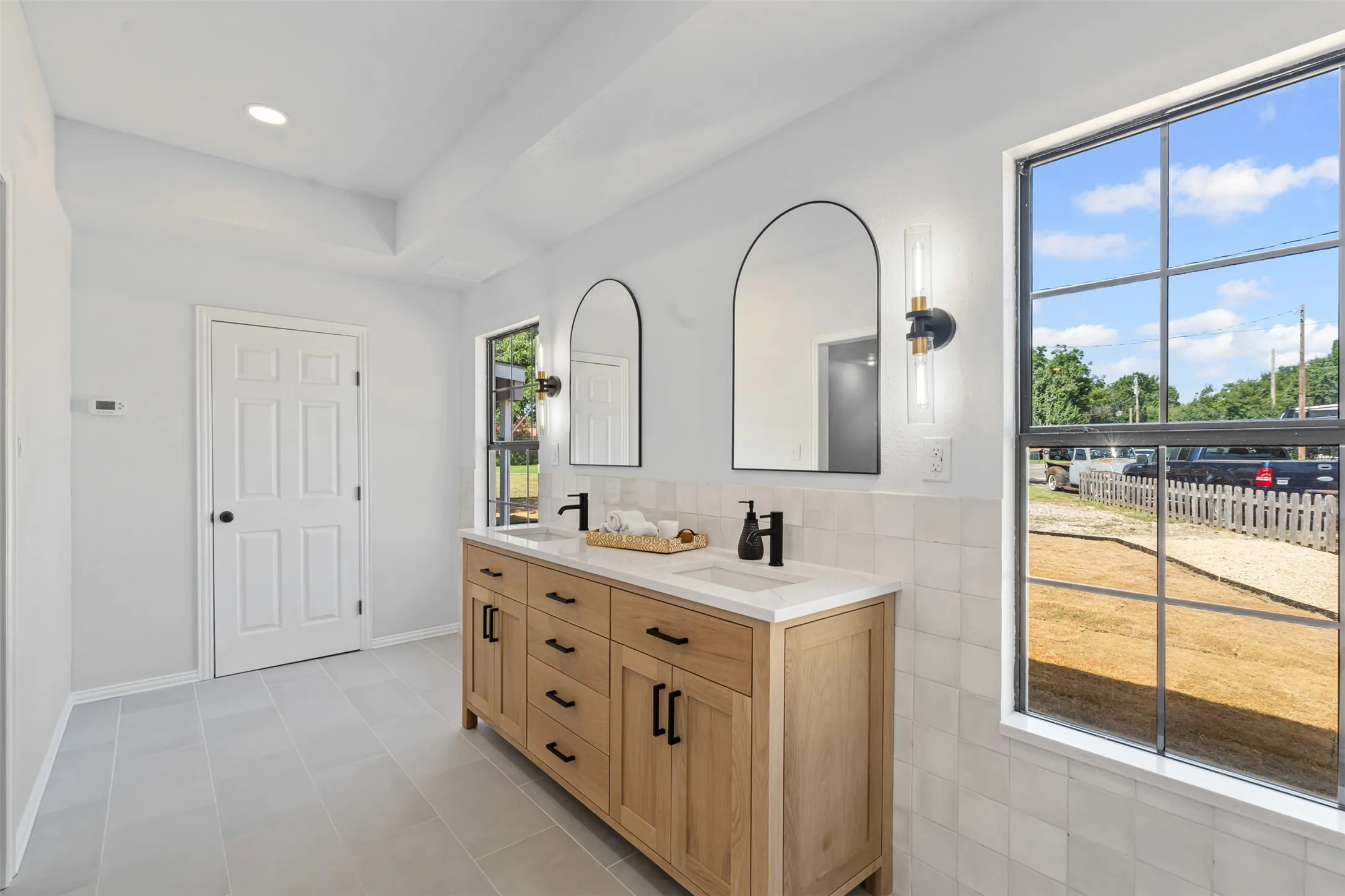 Bathroom featuring double vanity, tile walls, light tile patterned floors, and recessed lighting