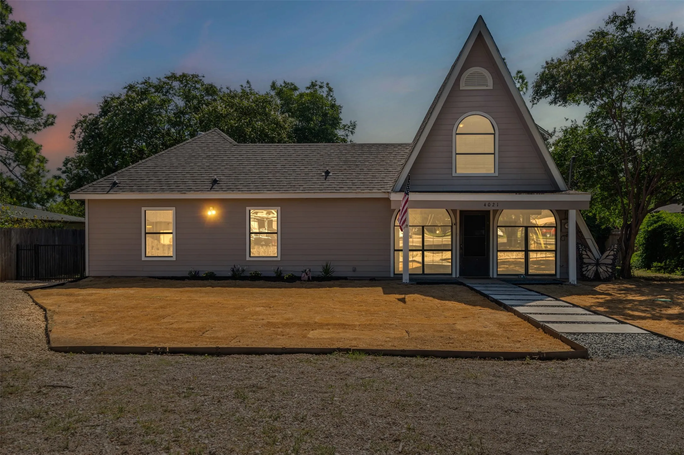 Back of property at dusk featuring a porch and a shingled roof