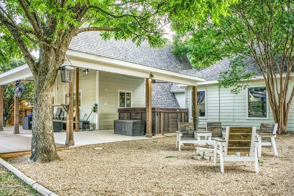 Back of house featuring roof with shingles, a hot tub, and a patio area