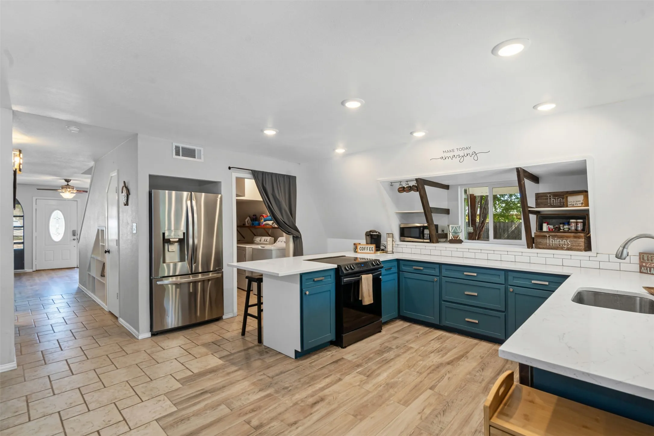 Kitchen with a peninsula, a kitchen breakfast bar, stainless steel appliances, light stone counters, and independent washer and dryer