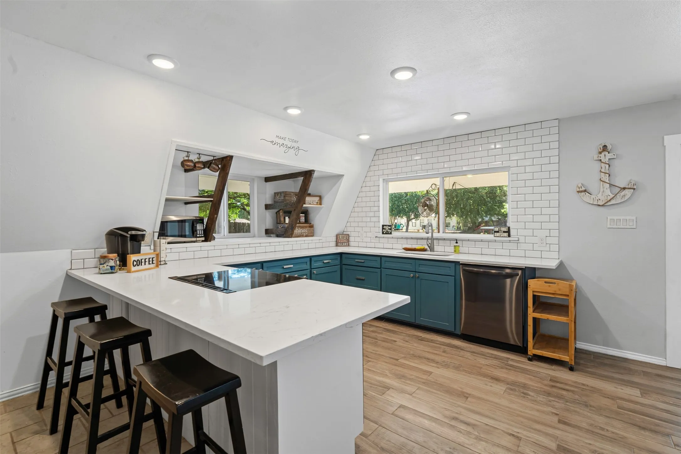 Kitchen featuring a breakfast bar area, a peninsula, blue cabinets, tasteful backsplash, and light stone countertops