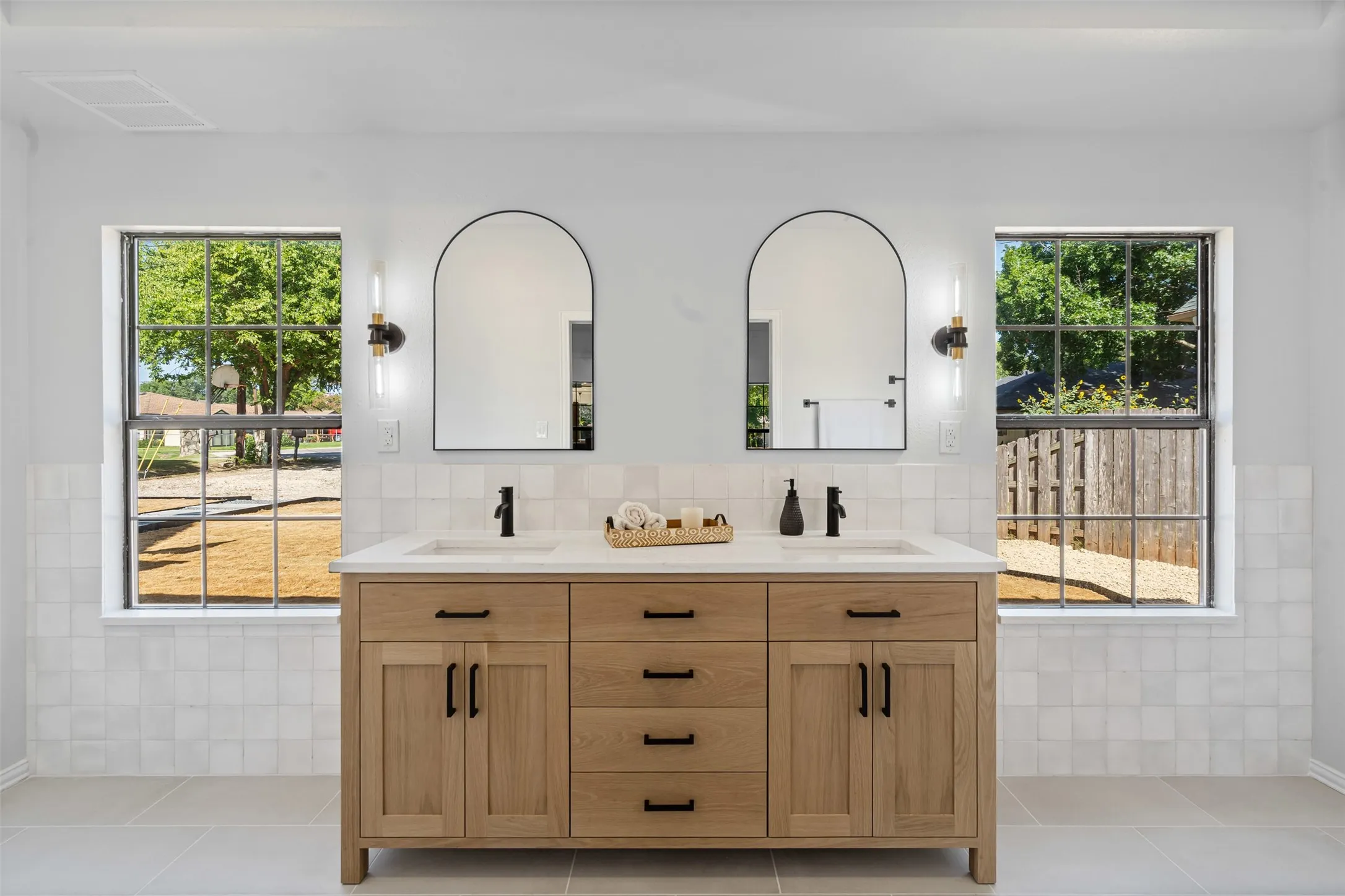 Bathroom with double vanity, tile walls, and light tile patterned flooring