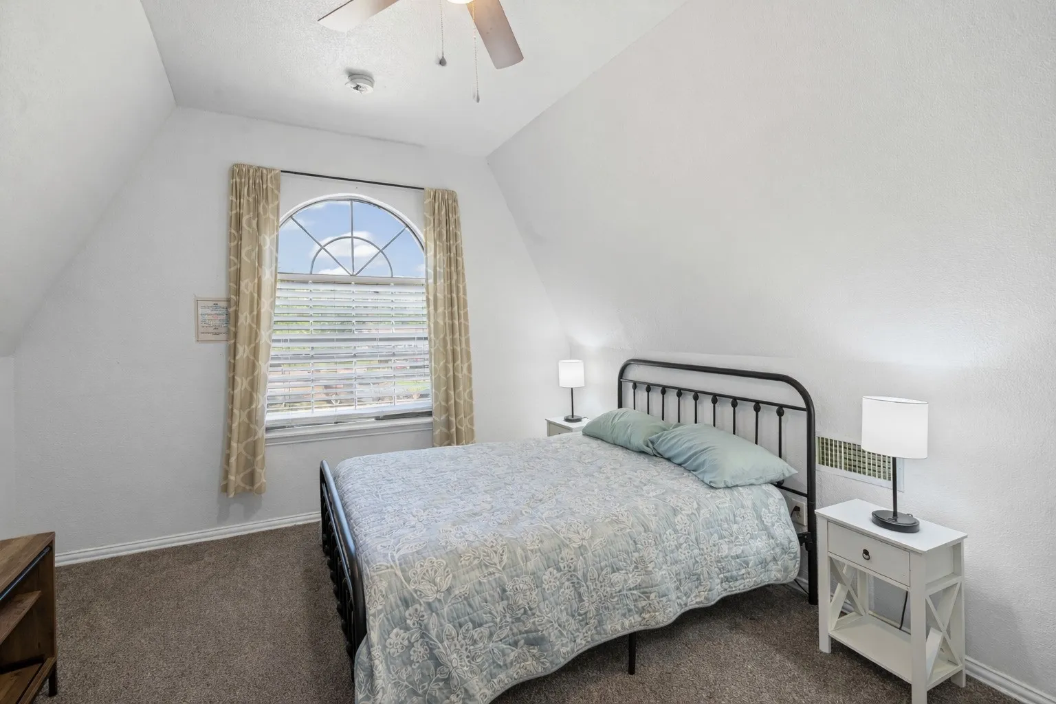 Bedroom with vaulted ceiling, dark colored carpet, and a ceiling fan