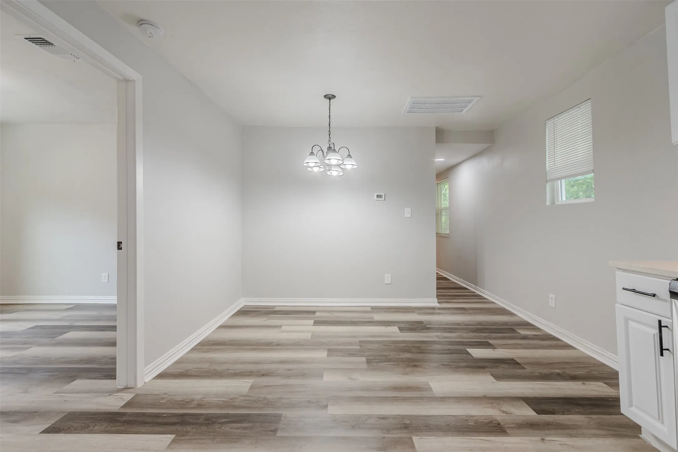 Unfurnished dining area featuring a chandelier and light wood-style flooring