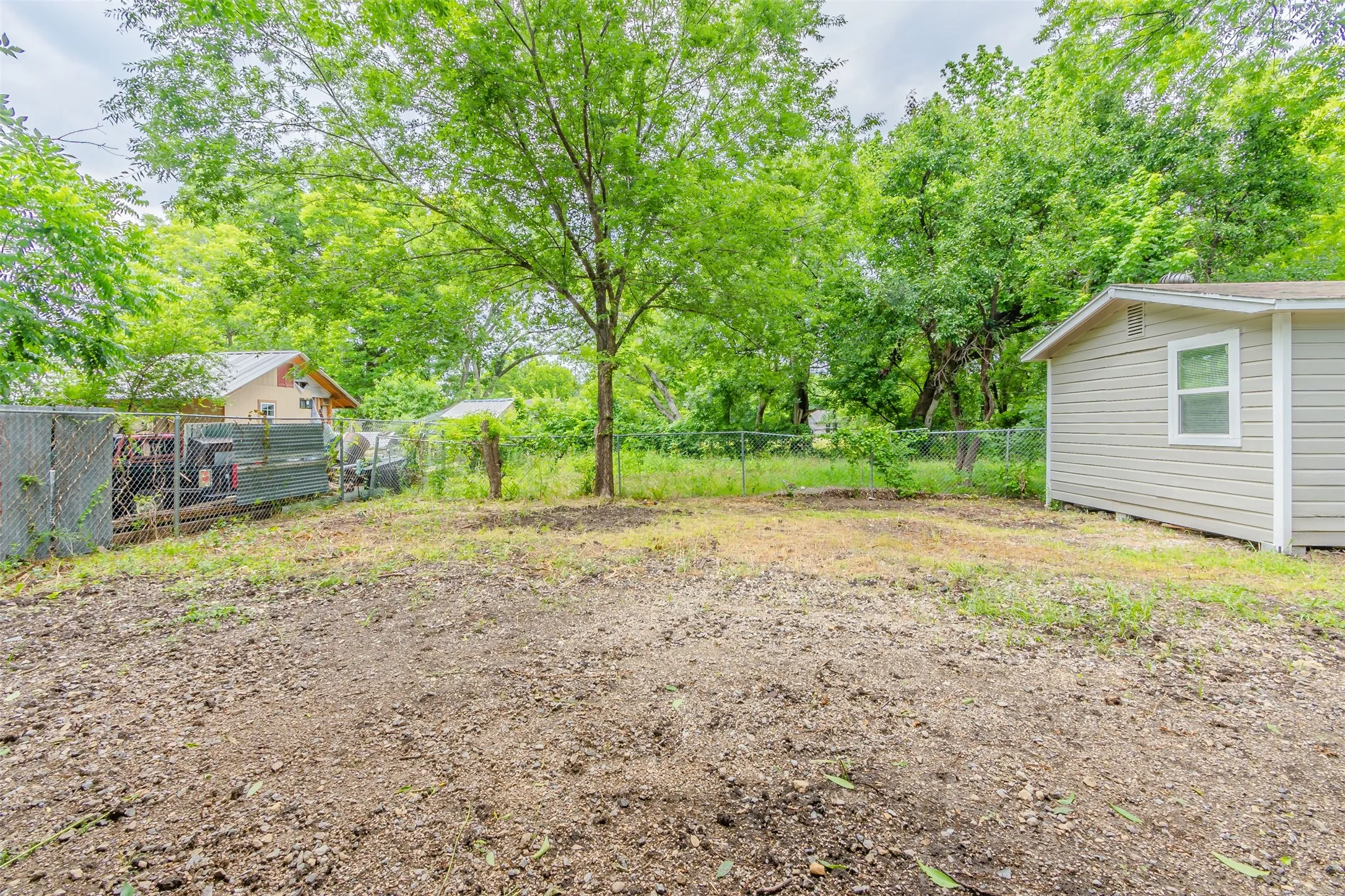 Fenced yard with view of wooded area
