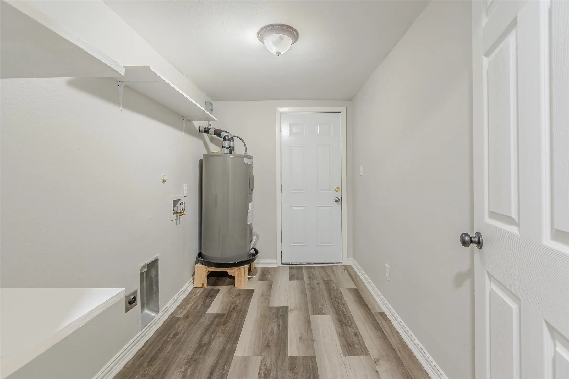 Laundry area with light wood-style floors, washer hookup, water heater, and electric dryer hookup