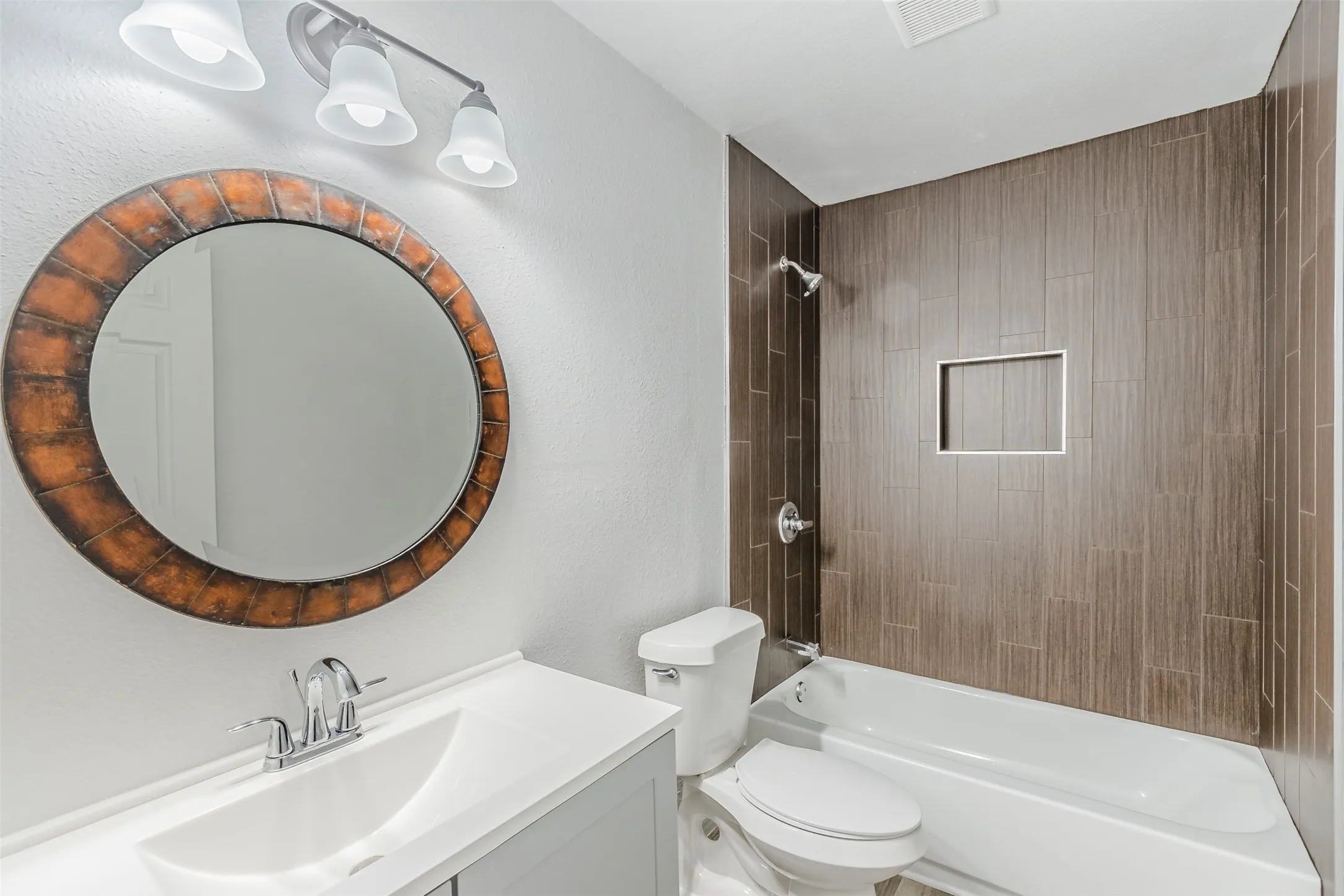 Full bathroom with vanity, bathing tub / shower combination, and a textured wall