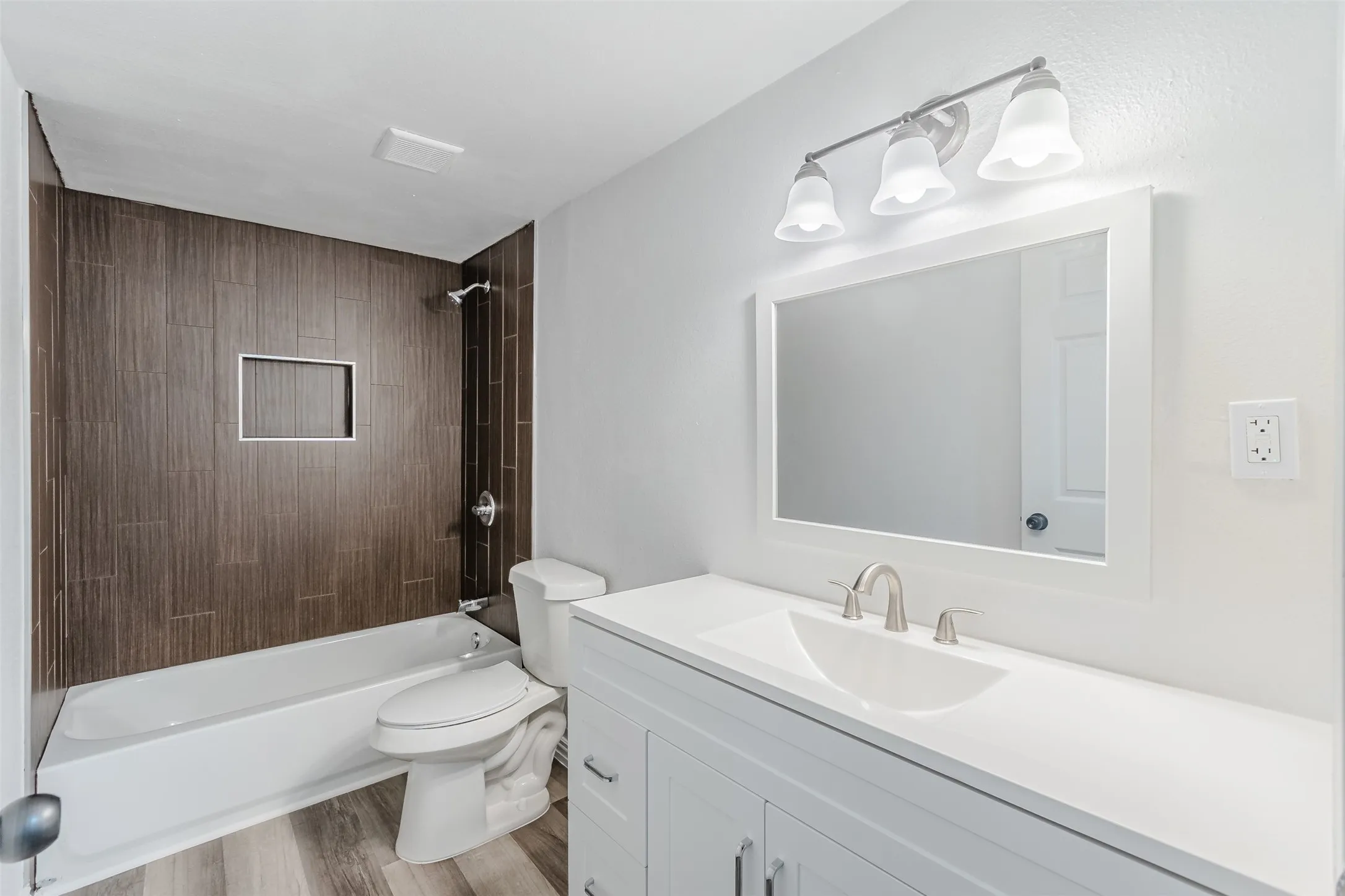 Full bathroom with vanity, washtub / shower combination, and light wood-style flooring