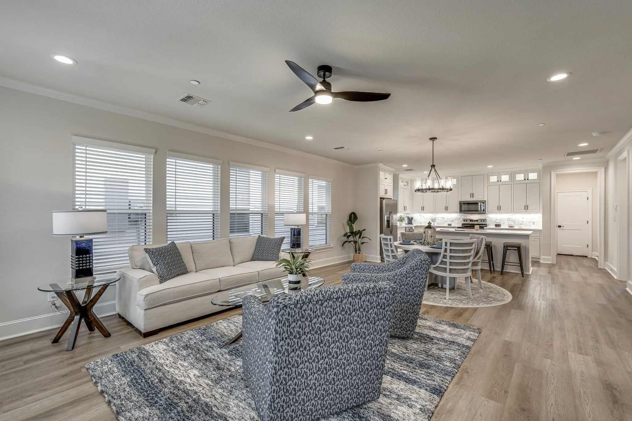 Living room with a ceiling fan, light wood-type flooring, ornamental molding, and a chandelier