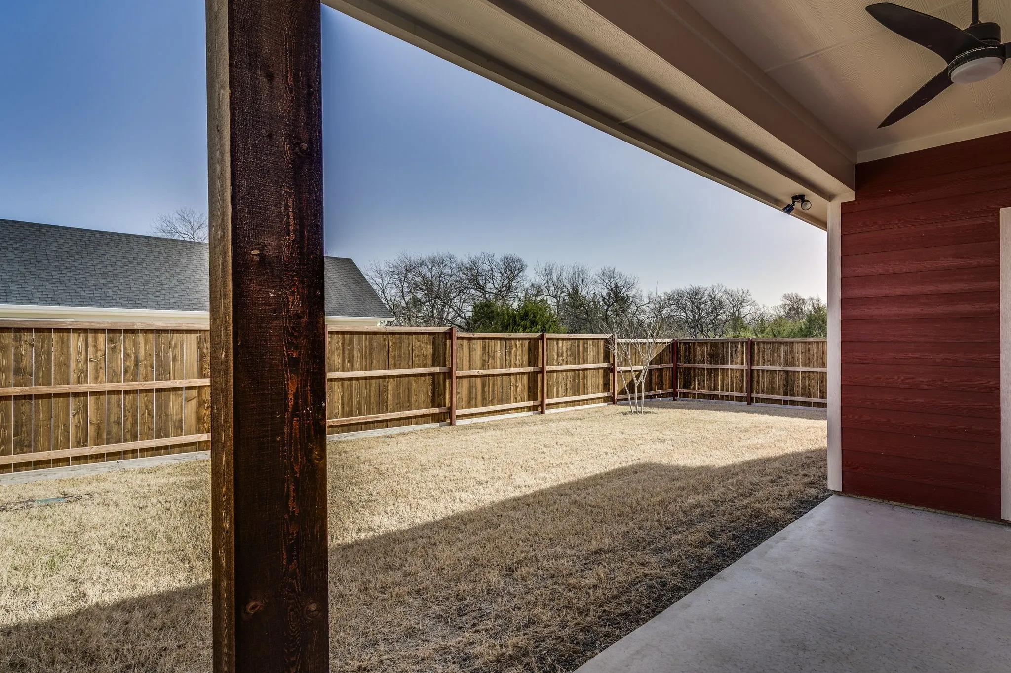 Fenced backyard featuring ceiling fan and a patio