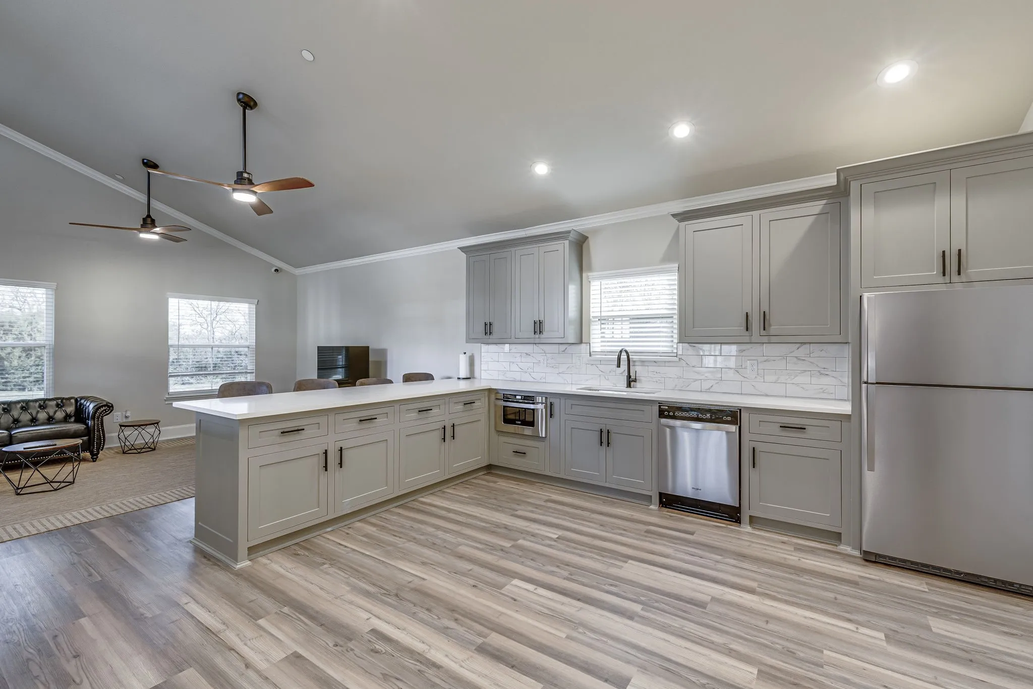 Kitchen with stainless steel appliances, a peninsula, lofted ceiling, tasteful backsplash, and a ceiling fan