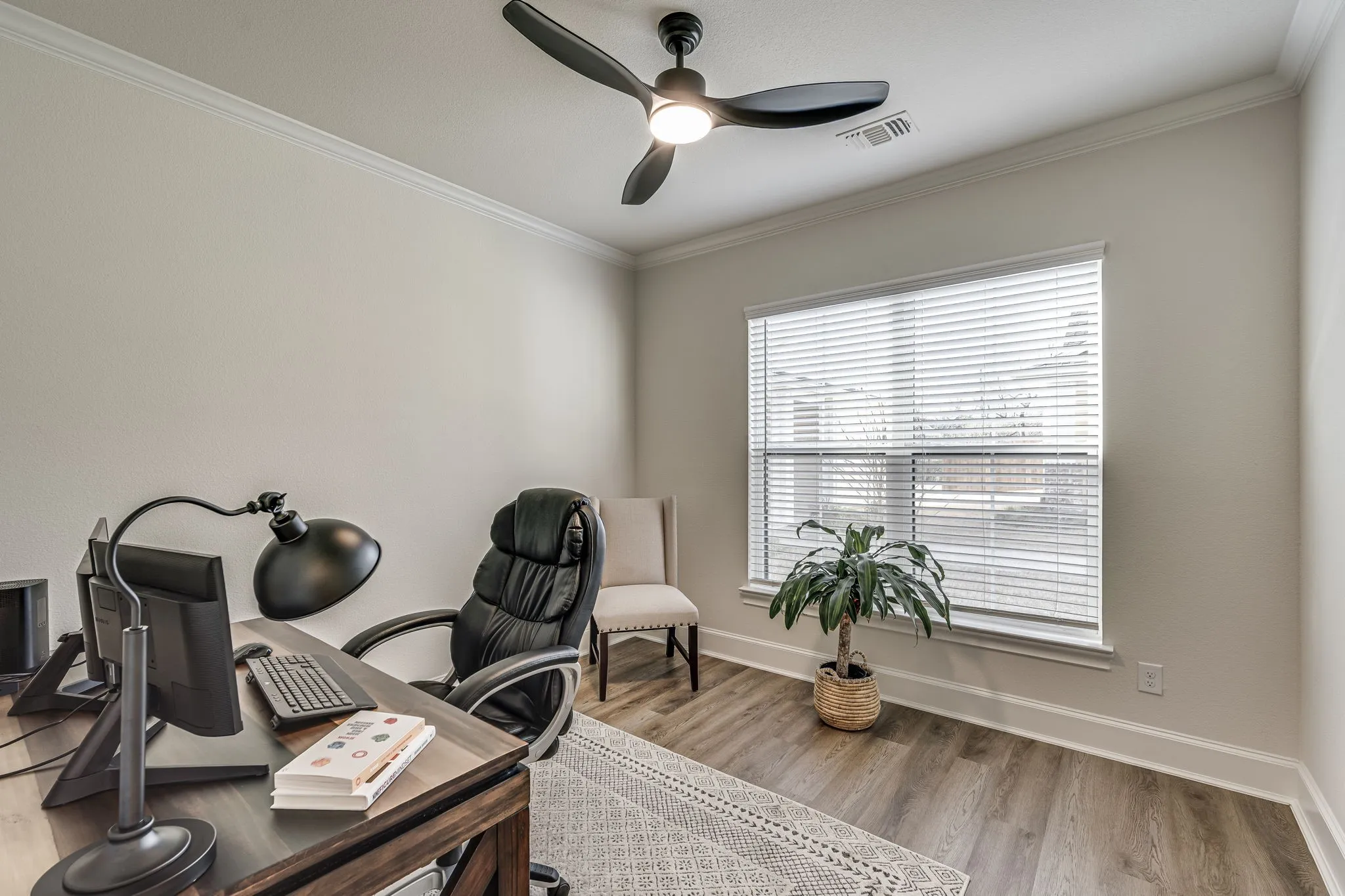 Office area with a ceiling fan, light wood finished floors, and crown molding