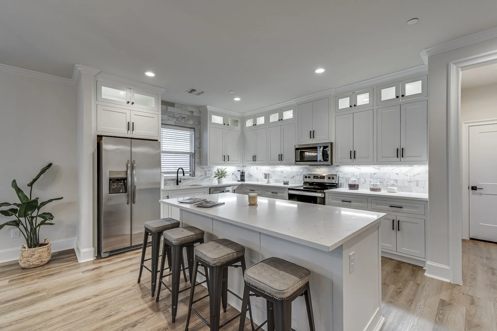 Kitchen with stainless steel appliances, ornamental molding, a breakfast bar area, white cabinetry, and light wood-style floors