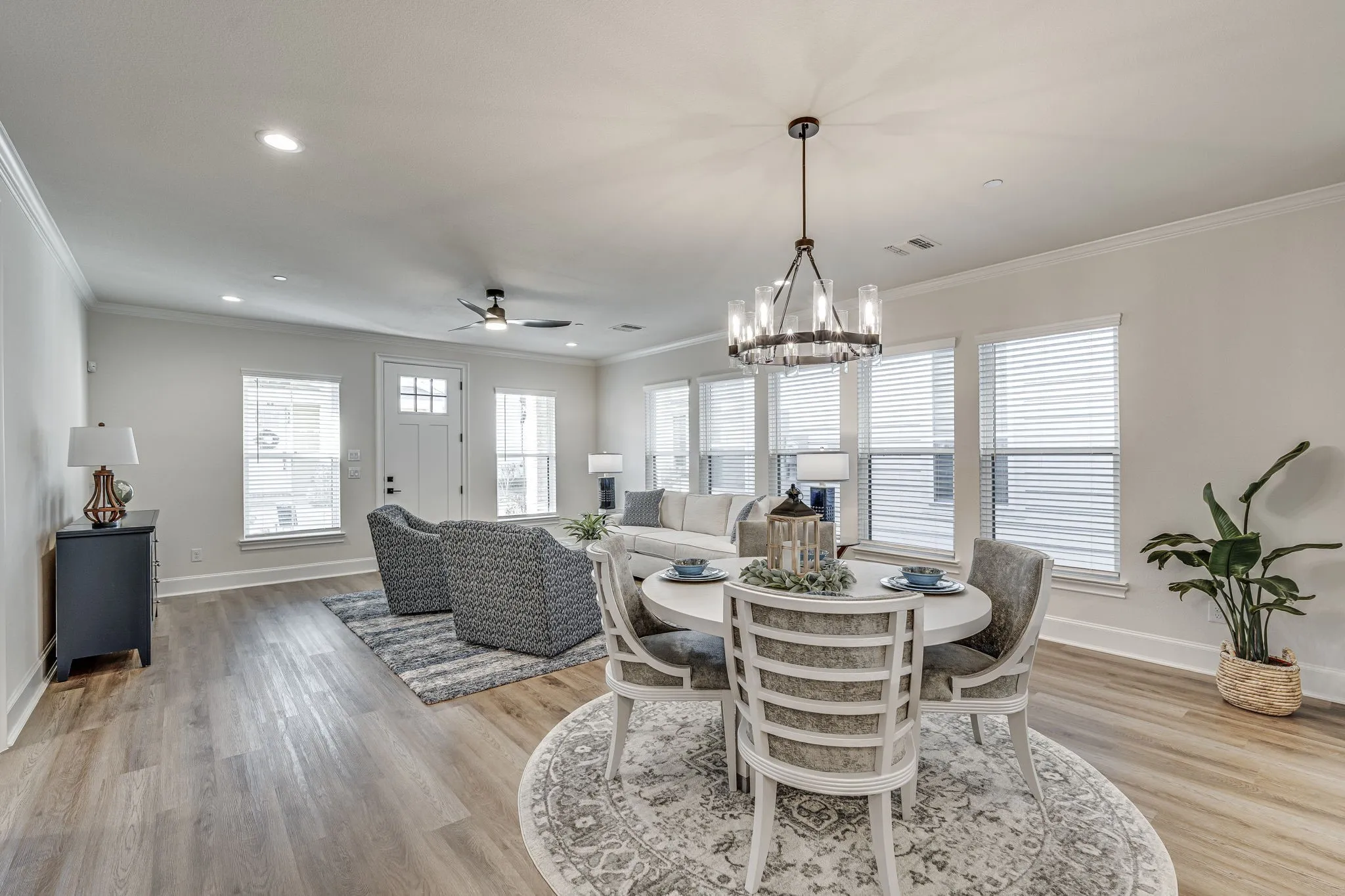 Dining area with ceiling fan, suspended lighting, crown molding, and light wood-type flooring