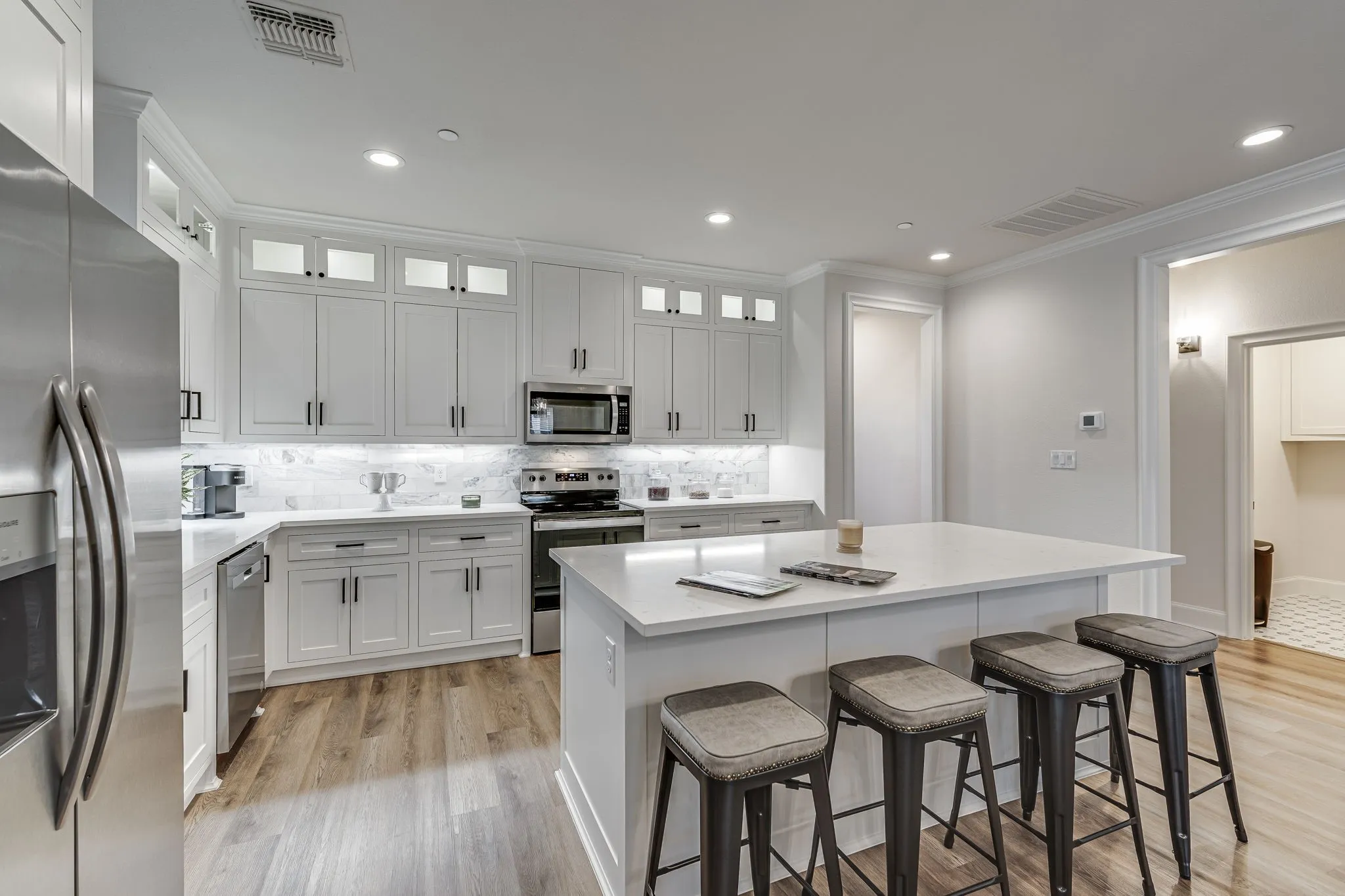 Kitchen featuring a breakfast bar area, stainless steel appliances, light wood finished floors, glass fronted cabinets, and a center island
