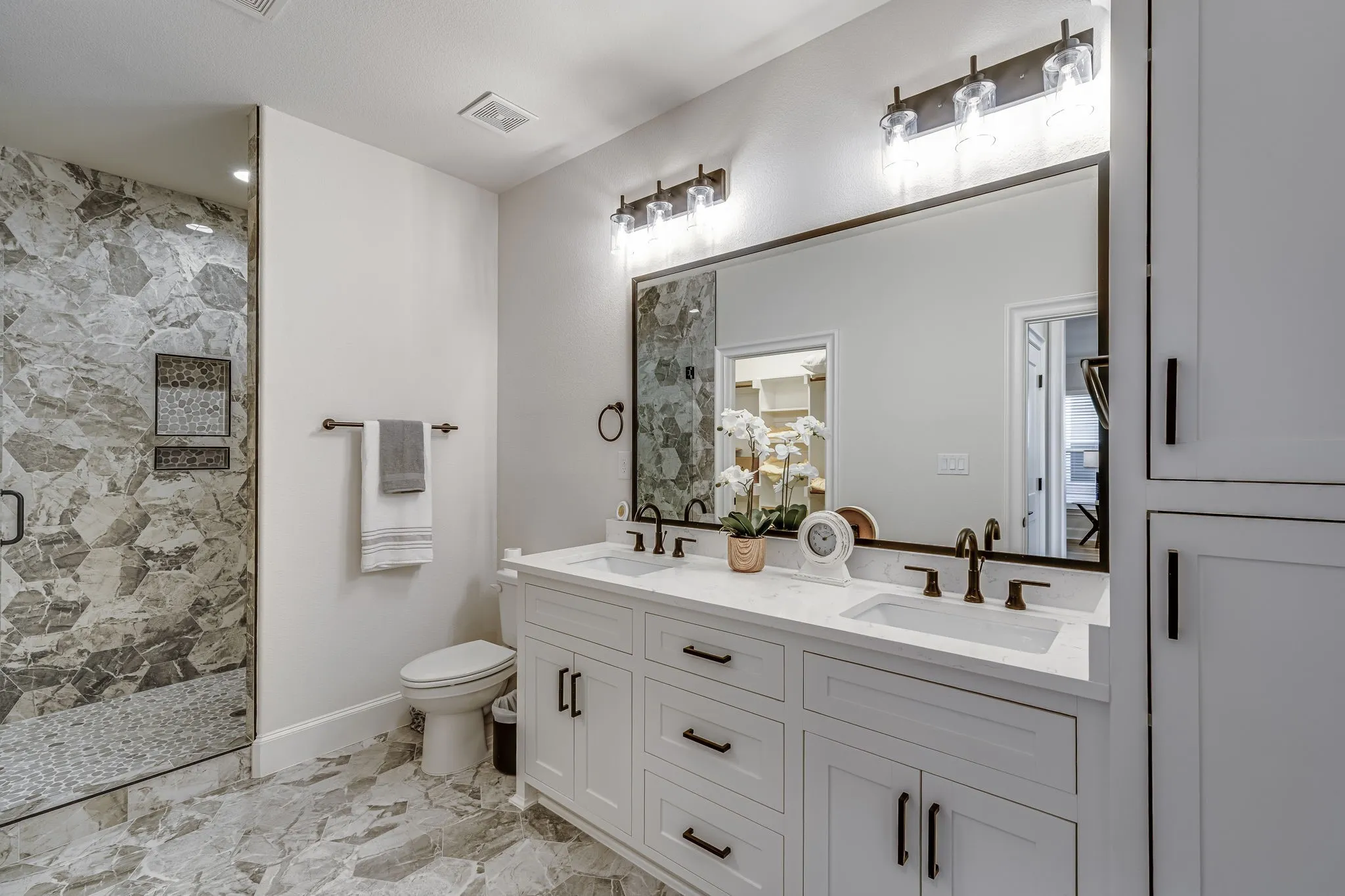 Full bathroom featuring double vanity and a marble finish shower
