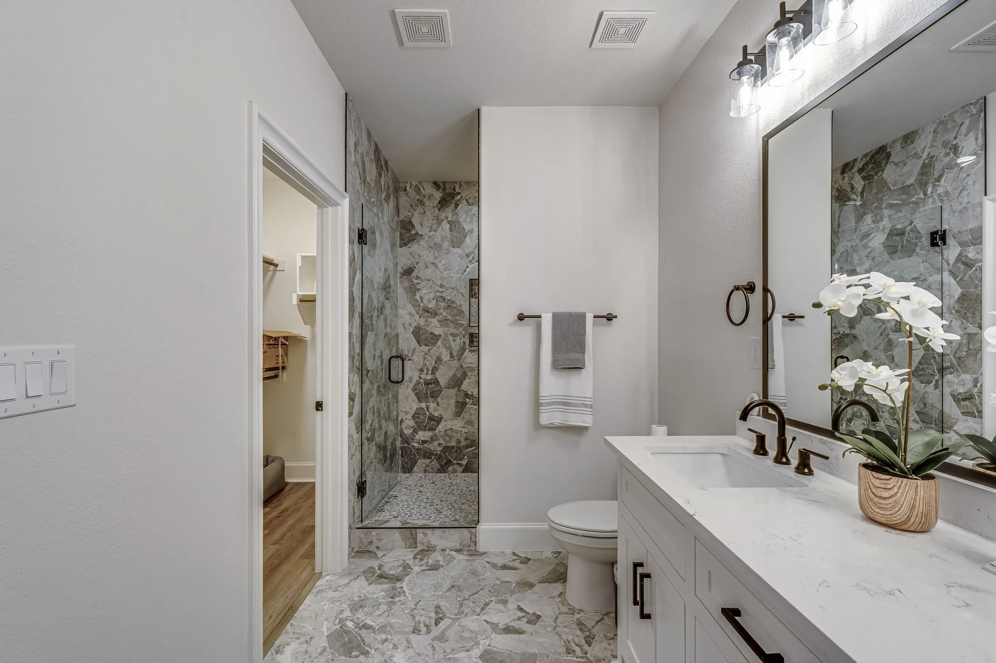 Bathroom with a marble finish shower, vanity, and a spacious closet