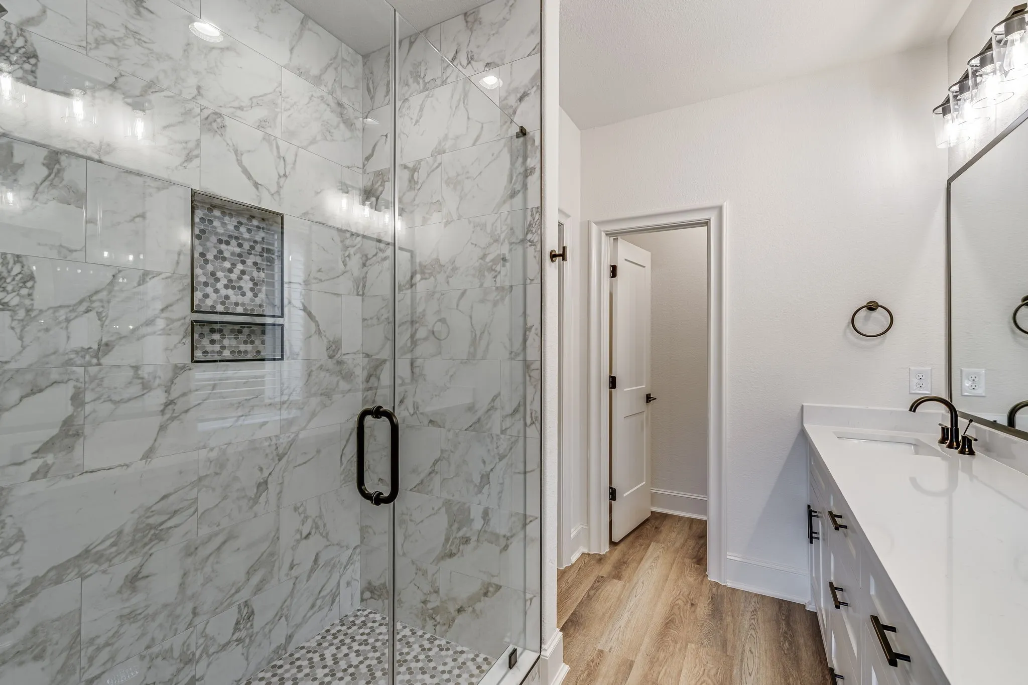 Bathroom featuring vanity, a marble finish shower, and light wood-style floors