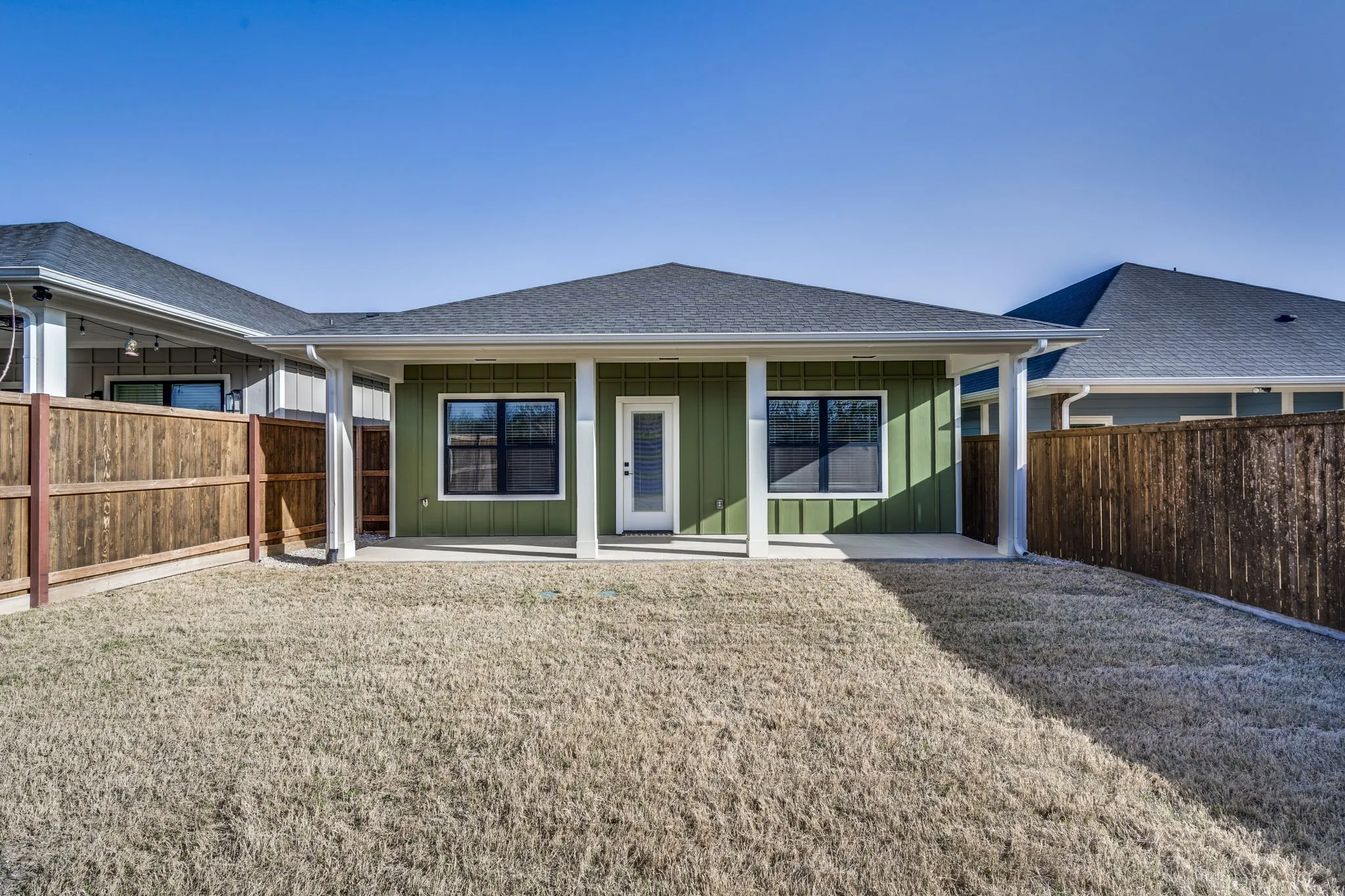 Back of house featuring board and batten siding, a shingled roof, and a patio area