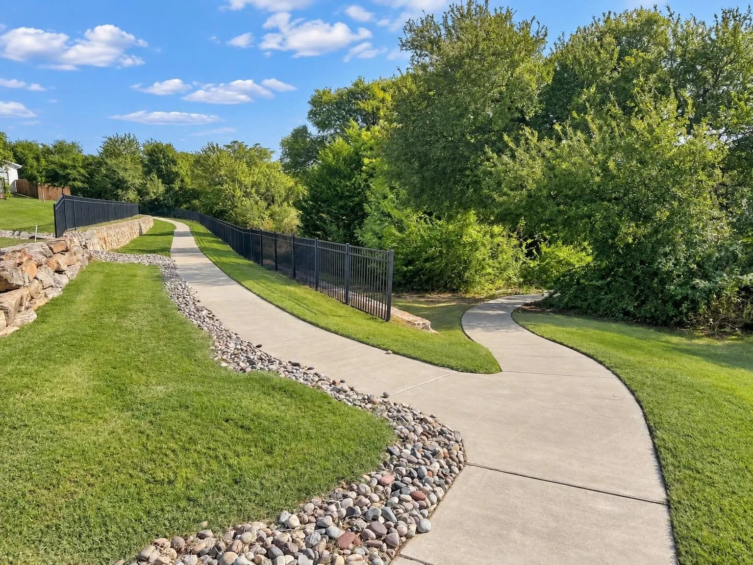 Paved pathways with a gentle curve, bordered by manicured lawn and decorative stone beds
