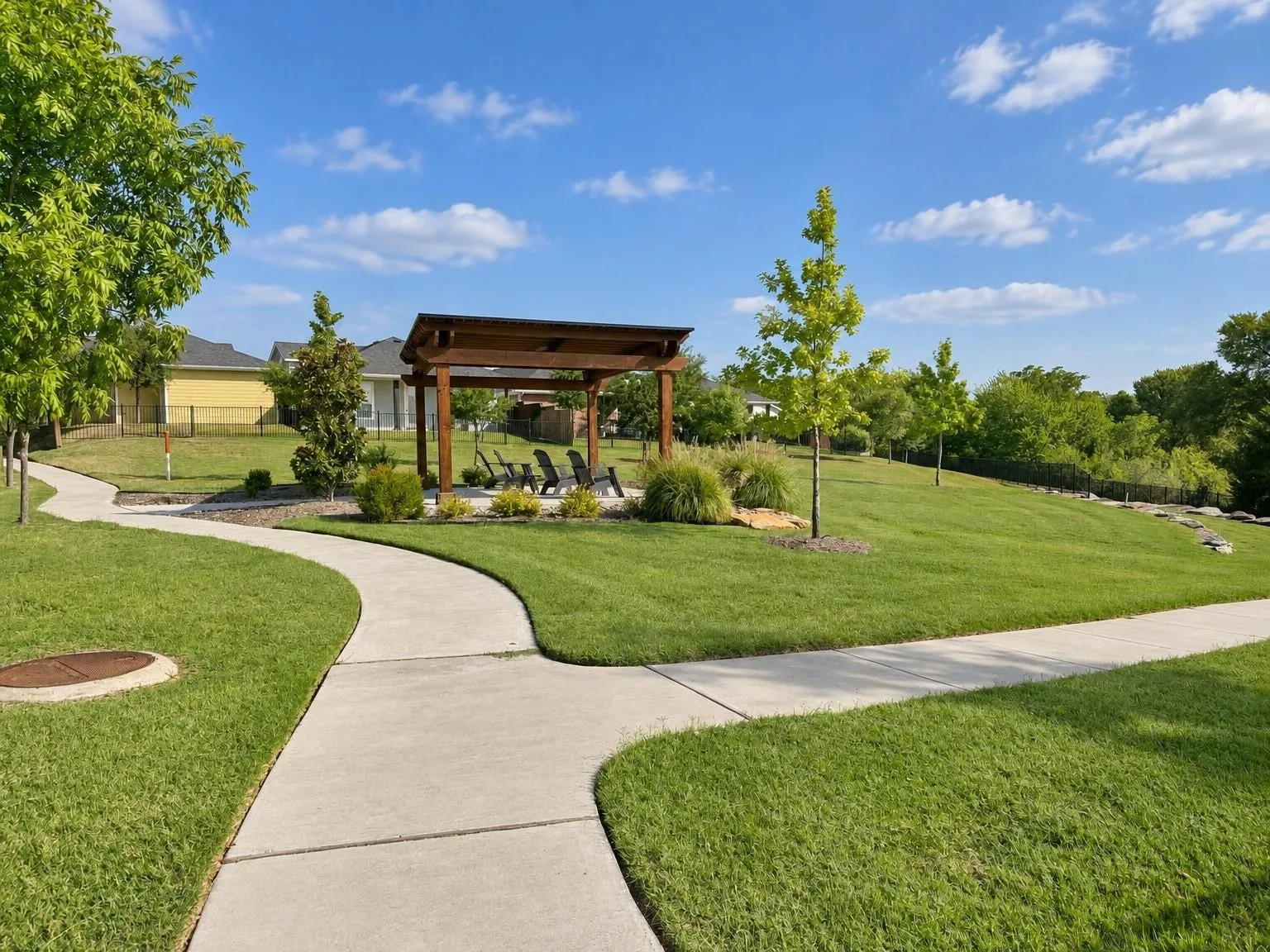 Curved concrete pathways, a wooden pergola, and mature trees define this landscaped green space