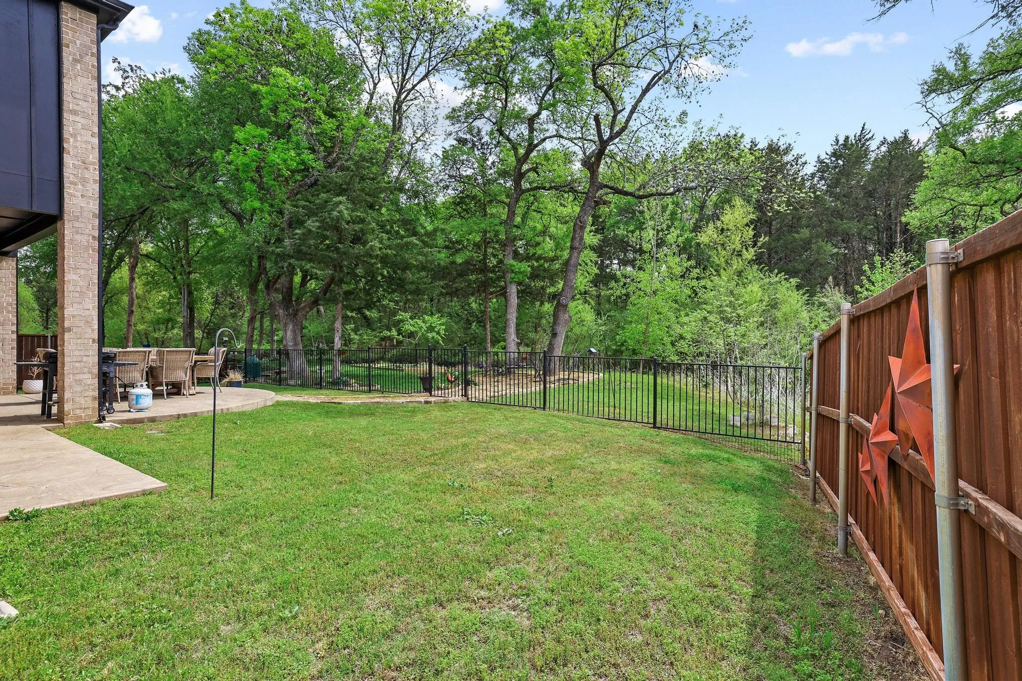 Fenced backyard featuring a patio and view of scattered trees