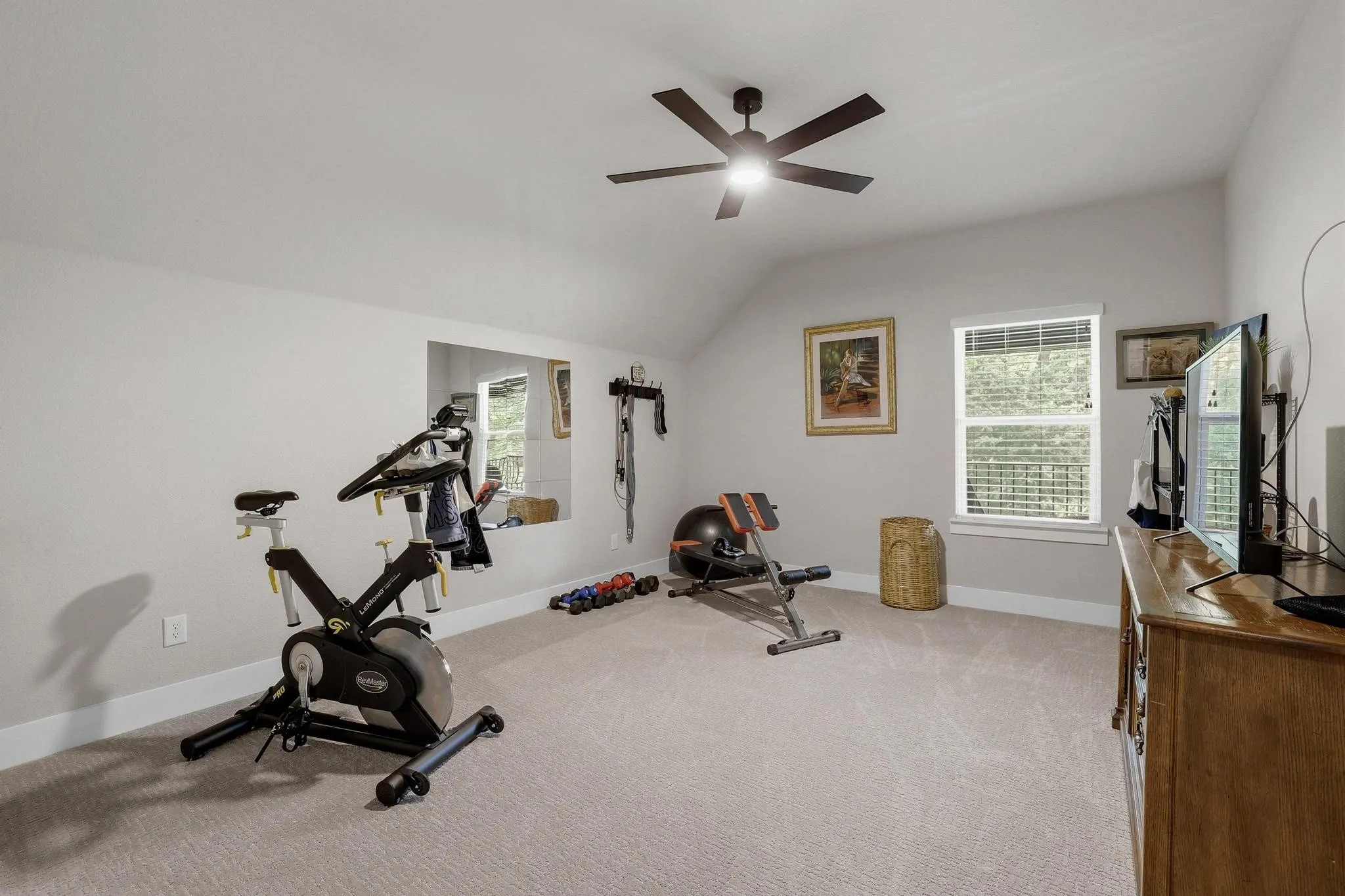 Workout area featuring light colored carpet, a ceiling fan, and lofted ceiling