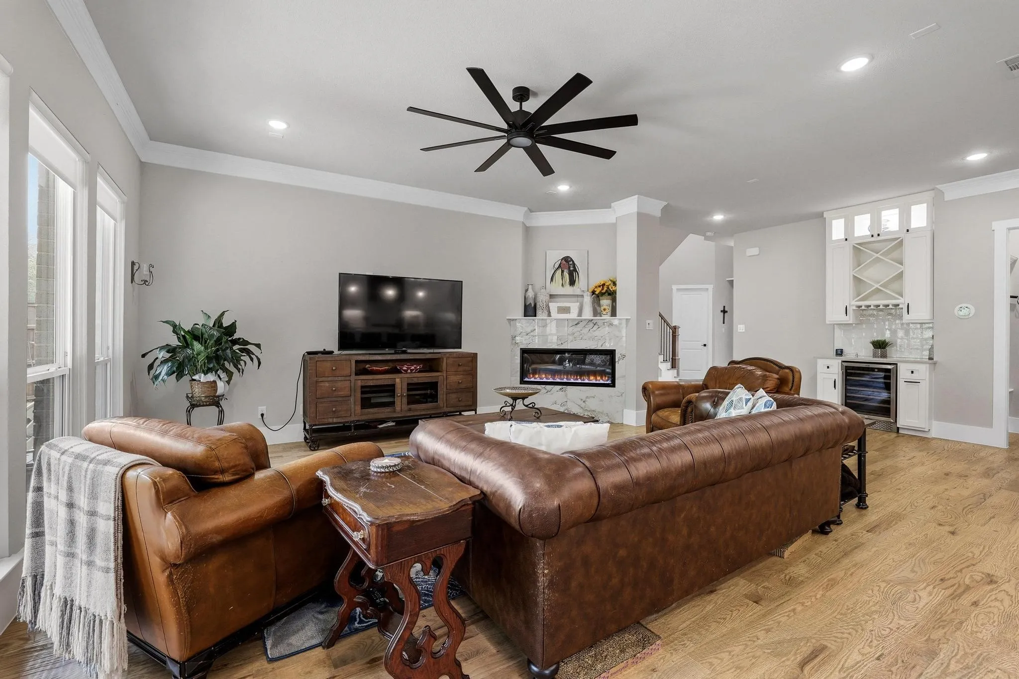 Living area featuring a dry bar, light wood-style floors, crown molding, a fireplace, and wine cooler