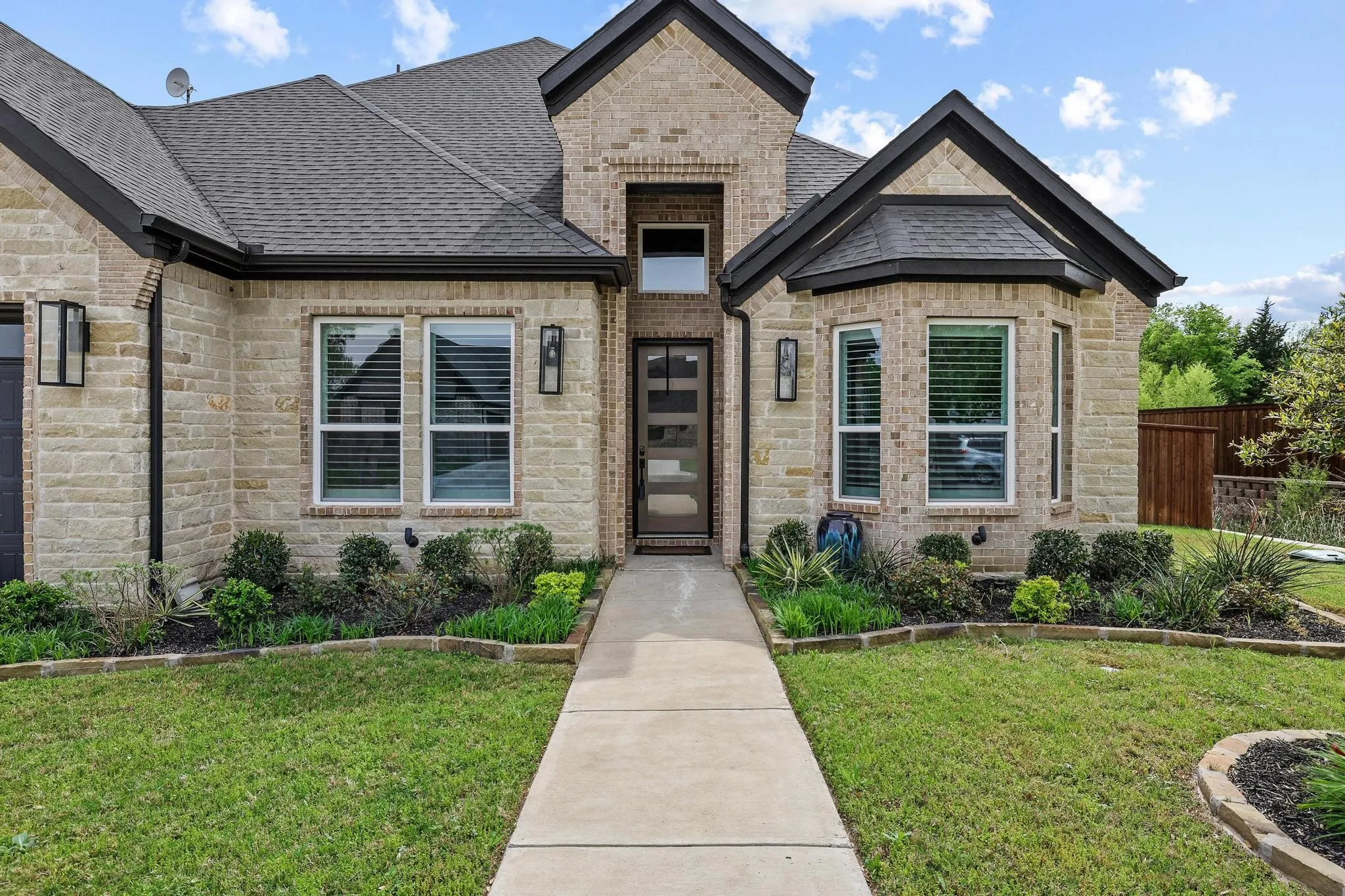 View of front of property featuring stone siding, a shingled roof, and brick siding