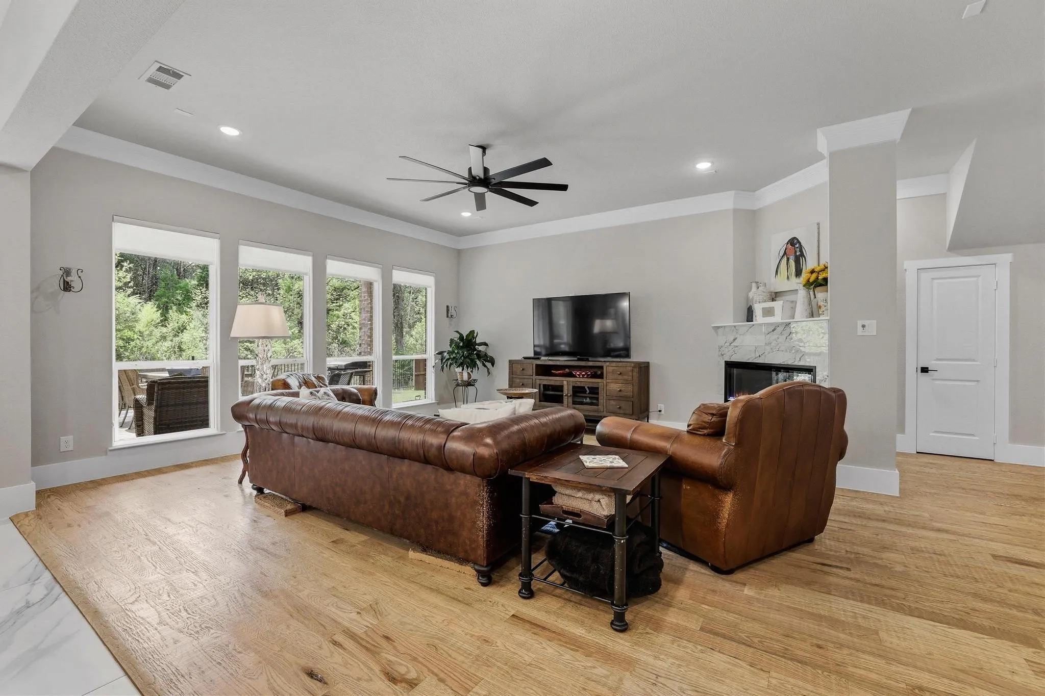 Living room with a premium fireplace, a ceiling fan, light wood finished floors, ornamental molding, and recessed lighting