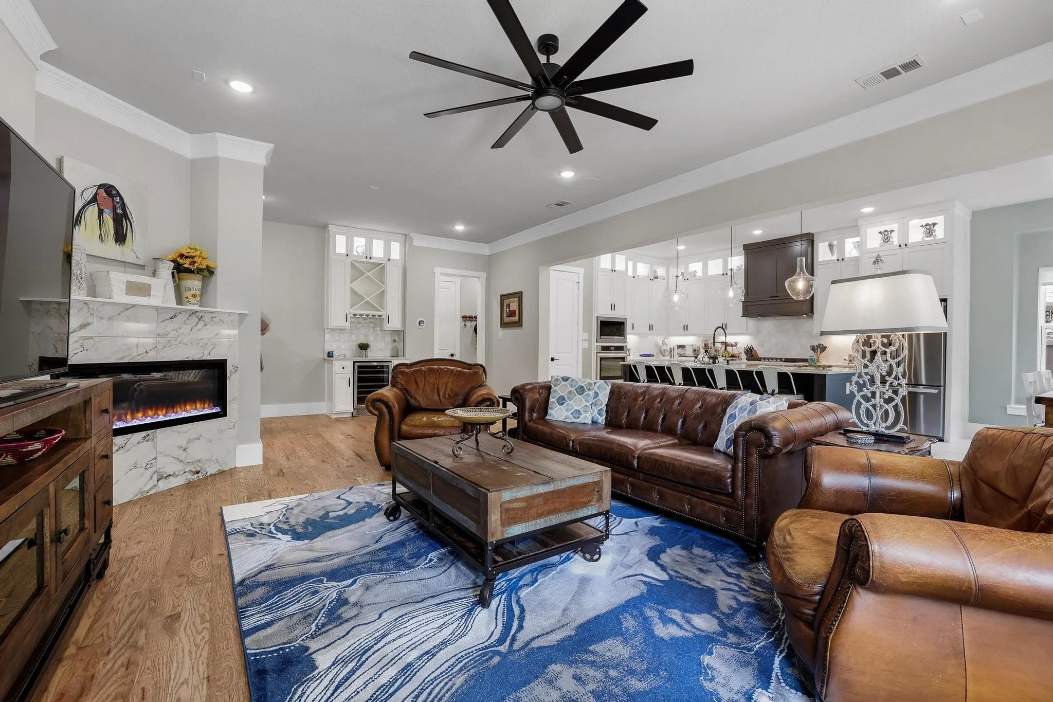 Living area featuring ornamental molding, a ceiling fan, wood finished floors, a fireplace, and beverage cooler