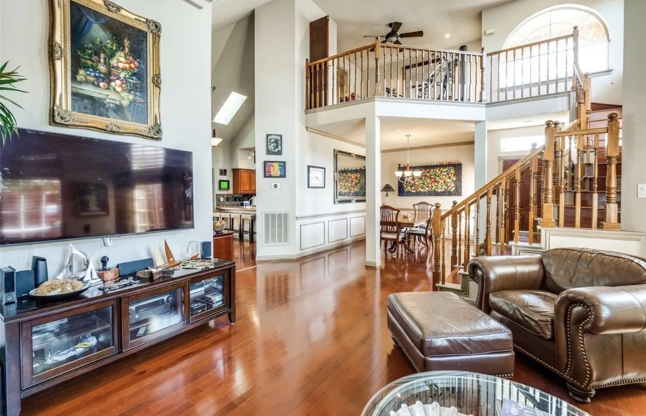 Living room with a high ceiling, wood finished floors, ceiling fan, a skylight, and suspended lighting
