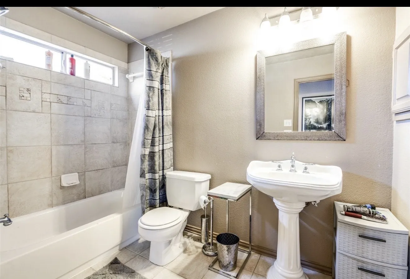 Full bathroom with a textured wall, shower / tub combo with curtain, and light tile patterned floors