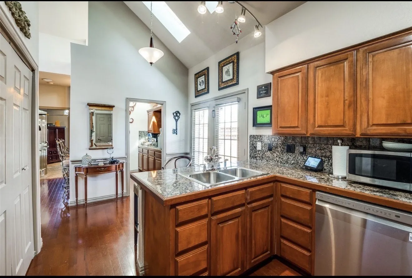 Kitchen with wood finish cabinets, stainless steel appliances, lofted ceiling, tasteful backsplash, and a skylight