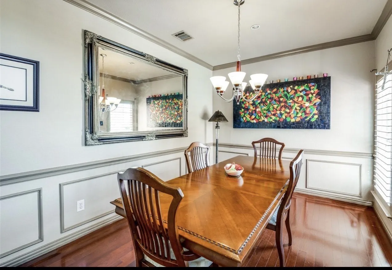 Dining space featuring a decorative wall, a wainscoted wall, wood finished floors, crown molding, and a chandelier
