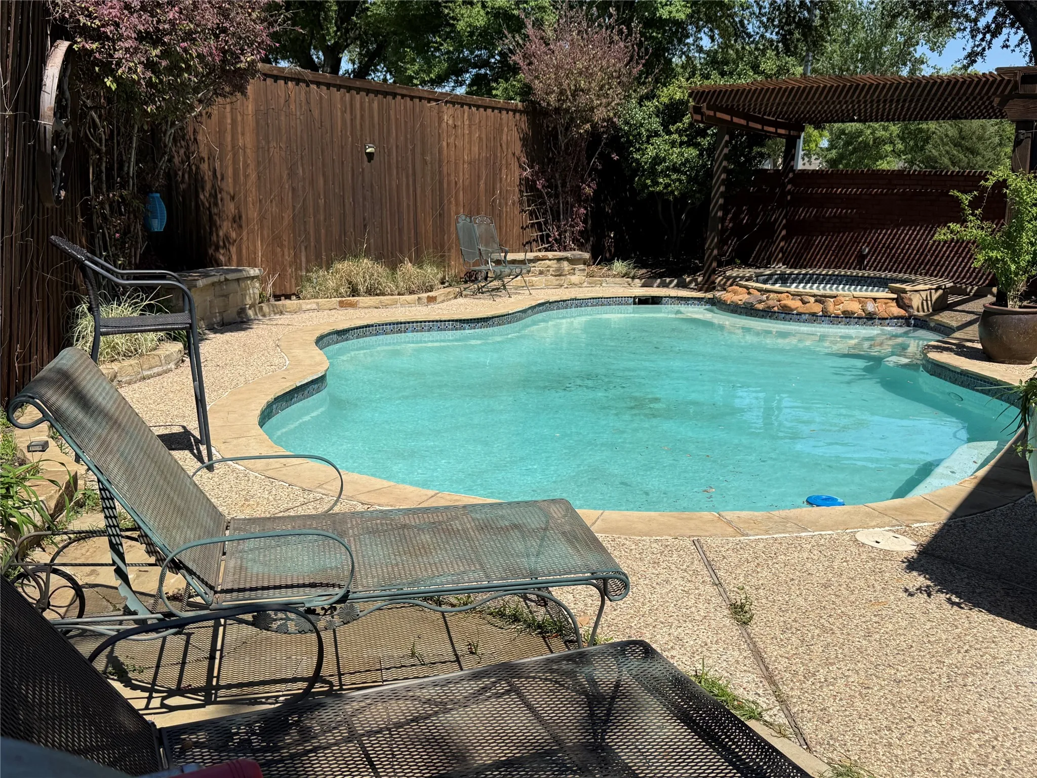 View of swimming pool featuring patio surround, a fenced backyard, and an in-ground hot tub