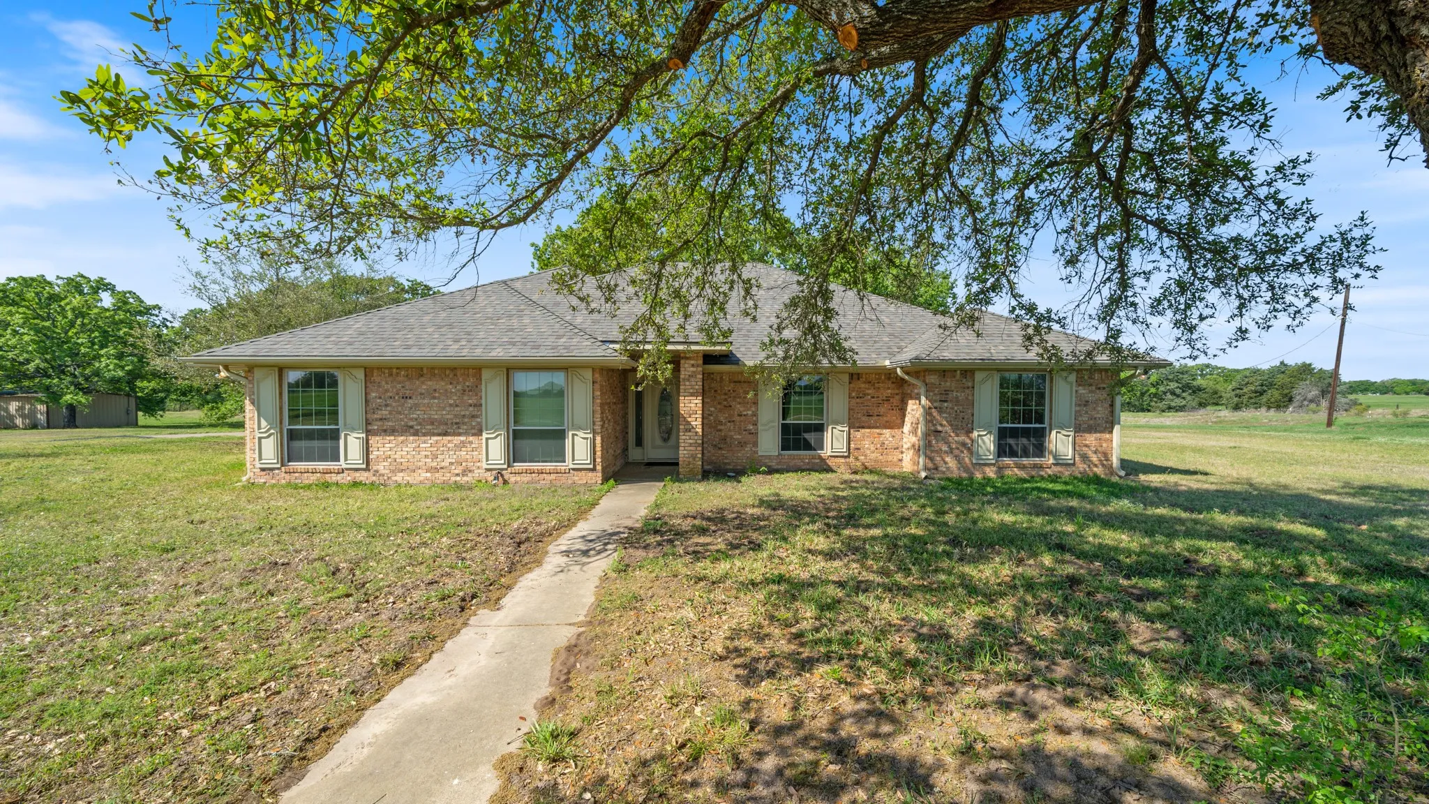 Ranch-style house with a front lawn, brick siding, and roof with shingles