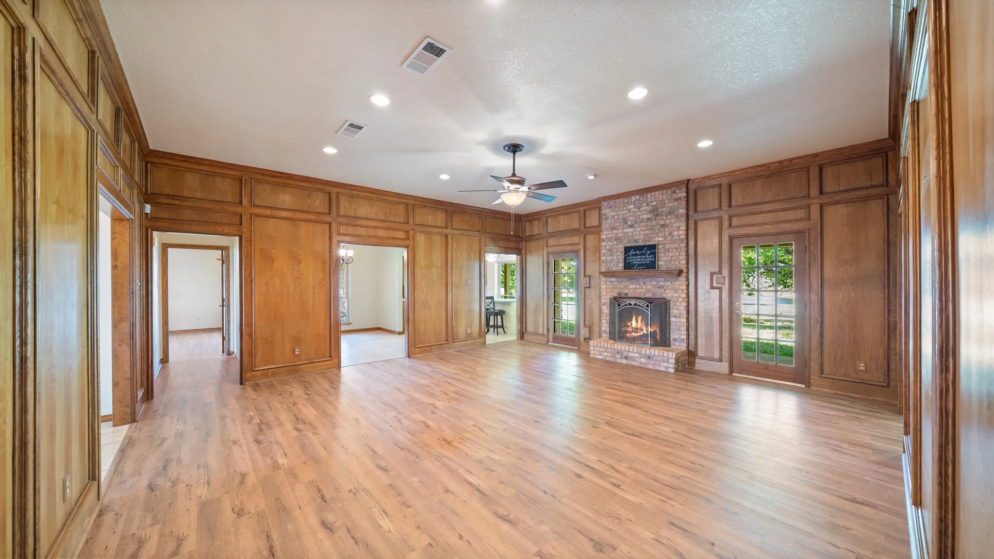 Unfurnished living room with recessed lighting, a ceiling fan, crown molding, light wood-type flooring, and a decorative wall