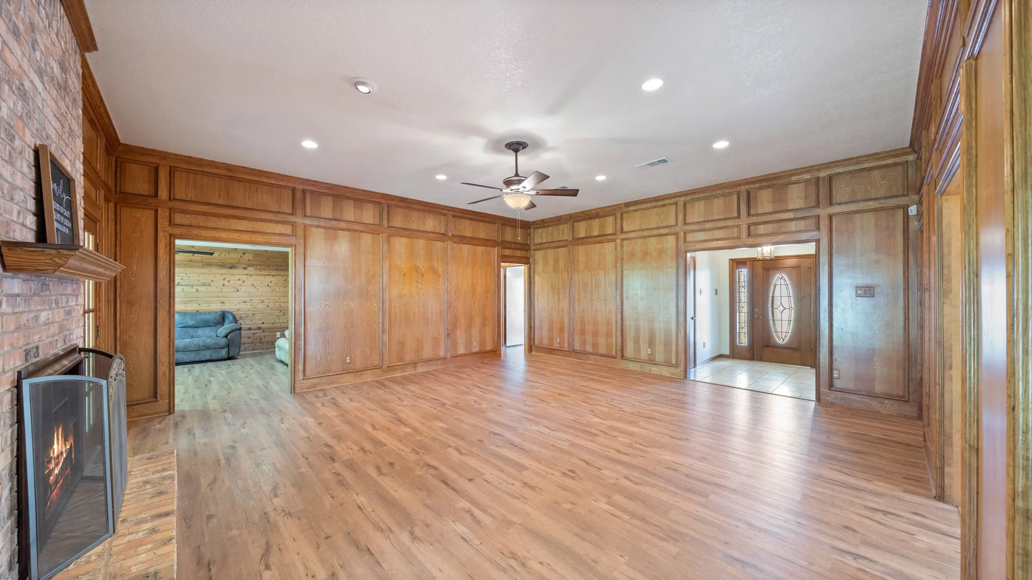 Unfurnished living room featuring light wood finished floors, recessed lighting, a ceiling fan, ornamental molding, and a fireplace
