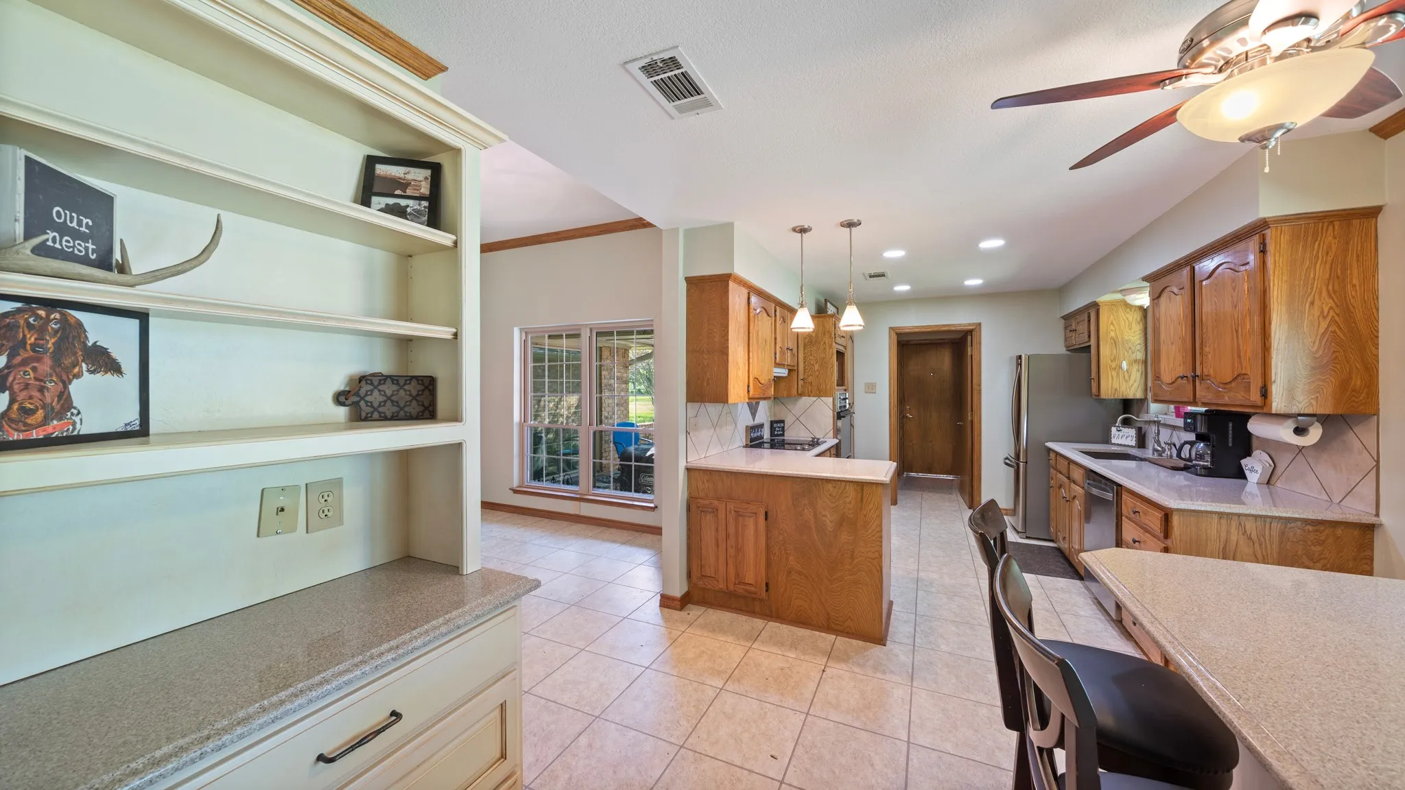 Kitchen featuring wood finish cabinets, ceiling fan, light tile patterned floors, and backsplash