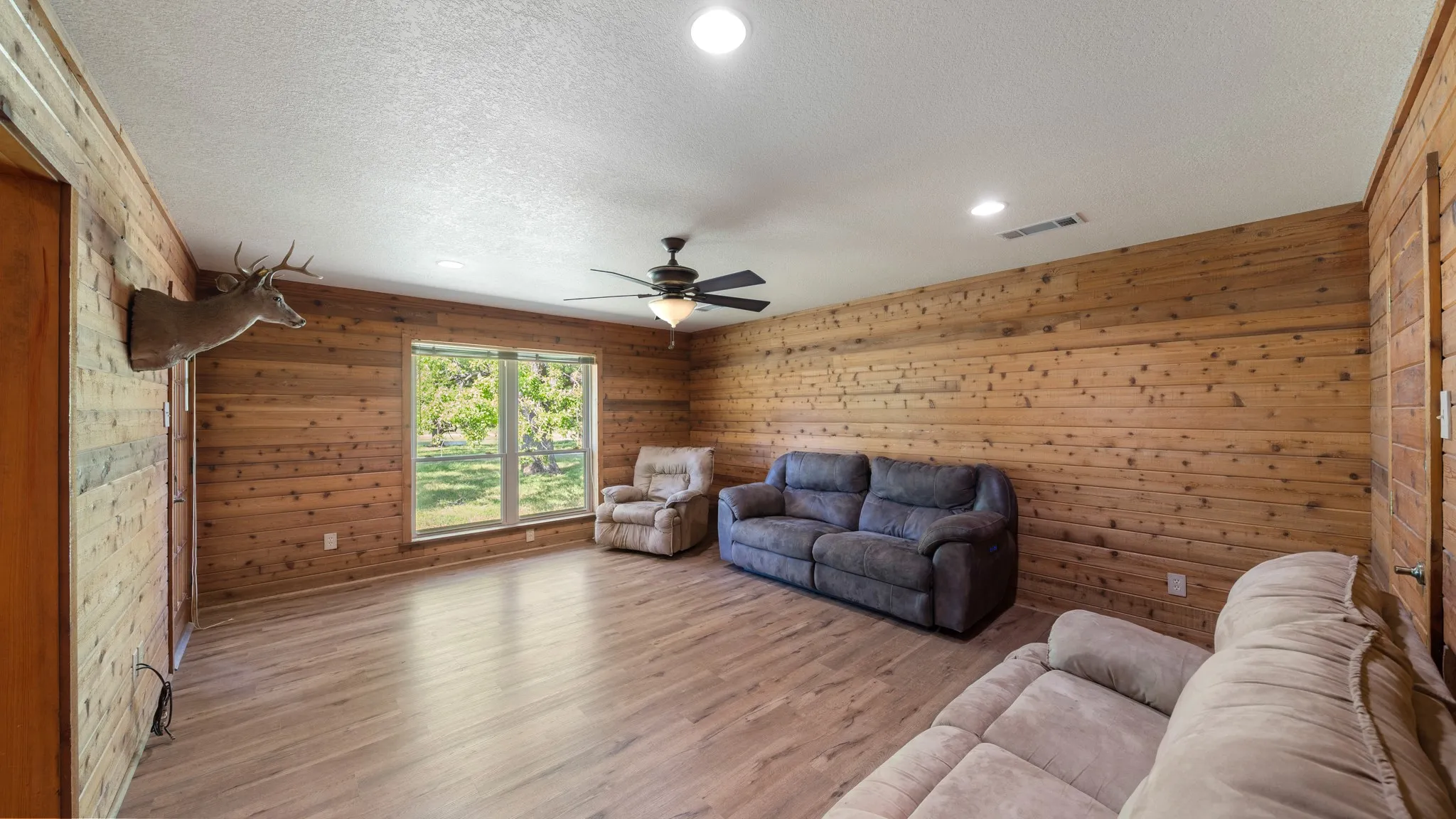 Living area with wood walls, a textured ceiling, wood finished floors, a ceiling fan, and recessed lighting with a closet