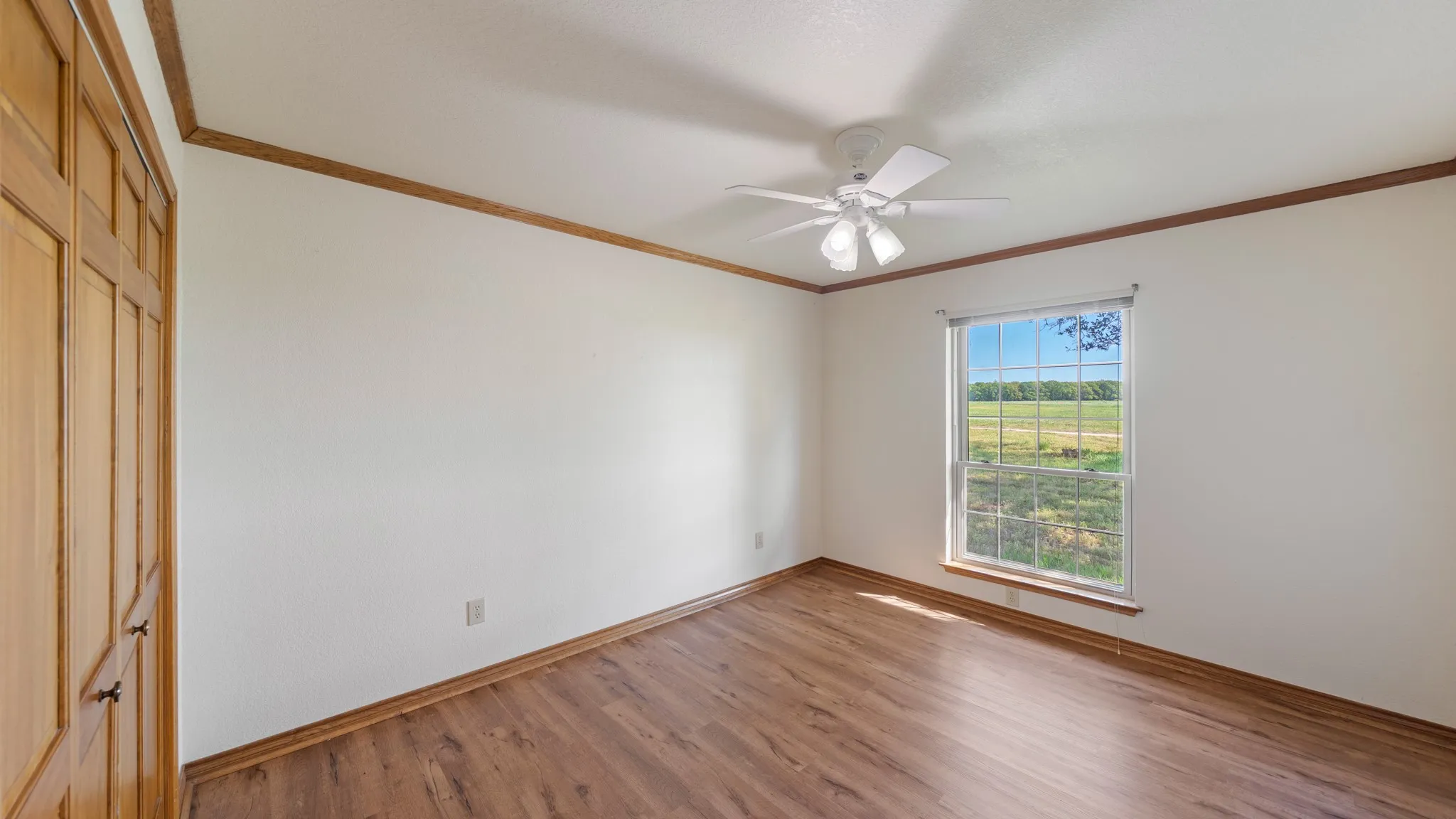 Unfurnished bedroom featuring a closet, light wood-type flooring, ornamental molding, and ceiling fan