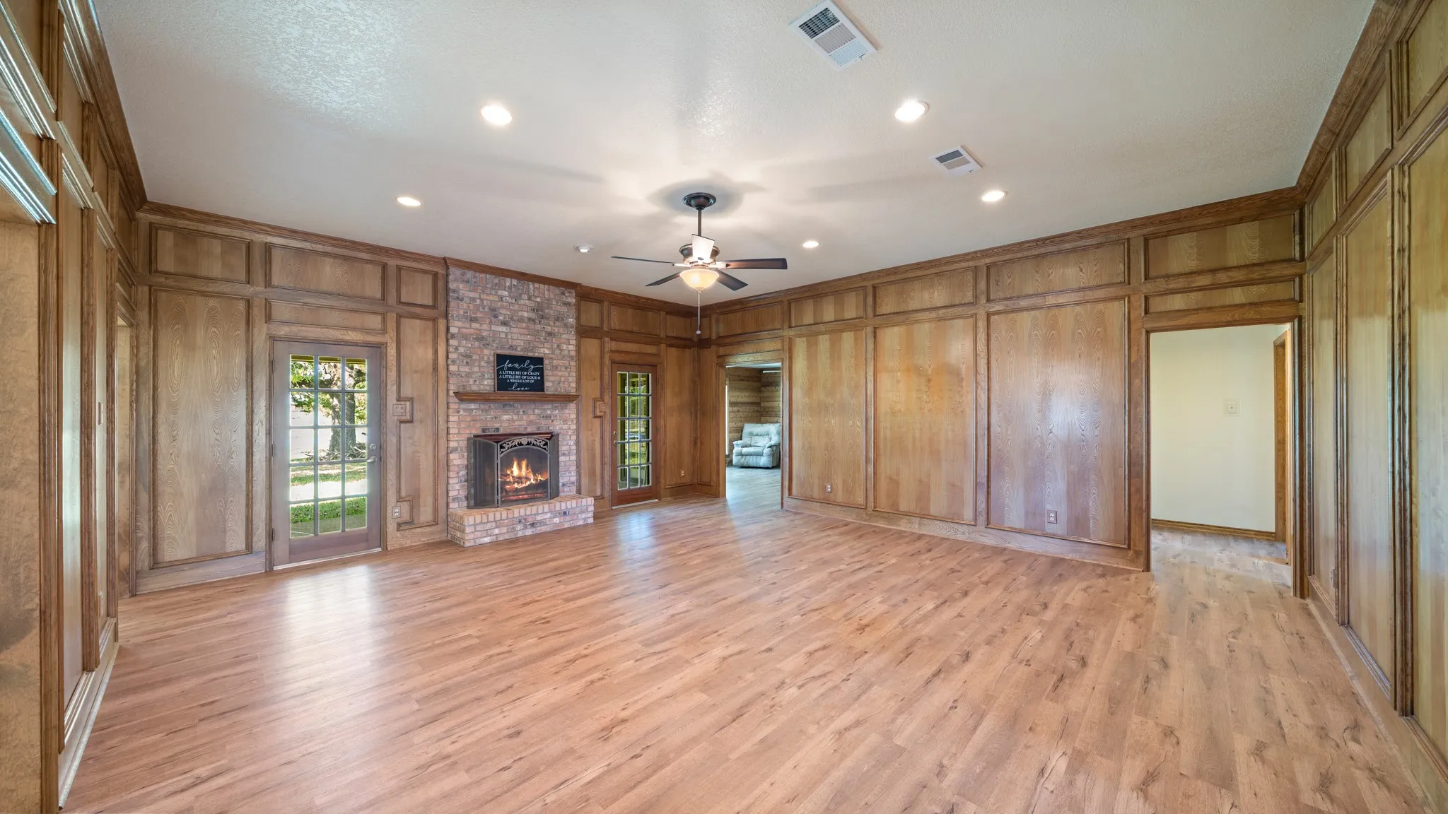 Unfurnished living room featuring ornamental molding, recessed lighting, a ceiling fan, light wood-type flooring, and a decorative wall