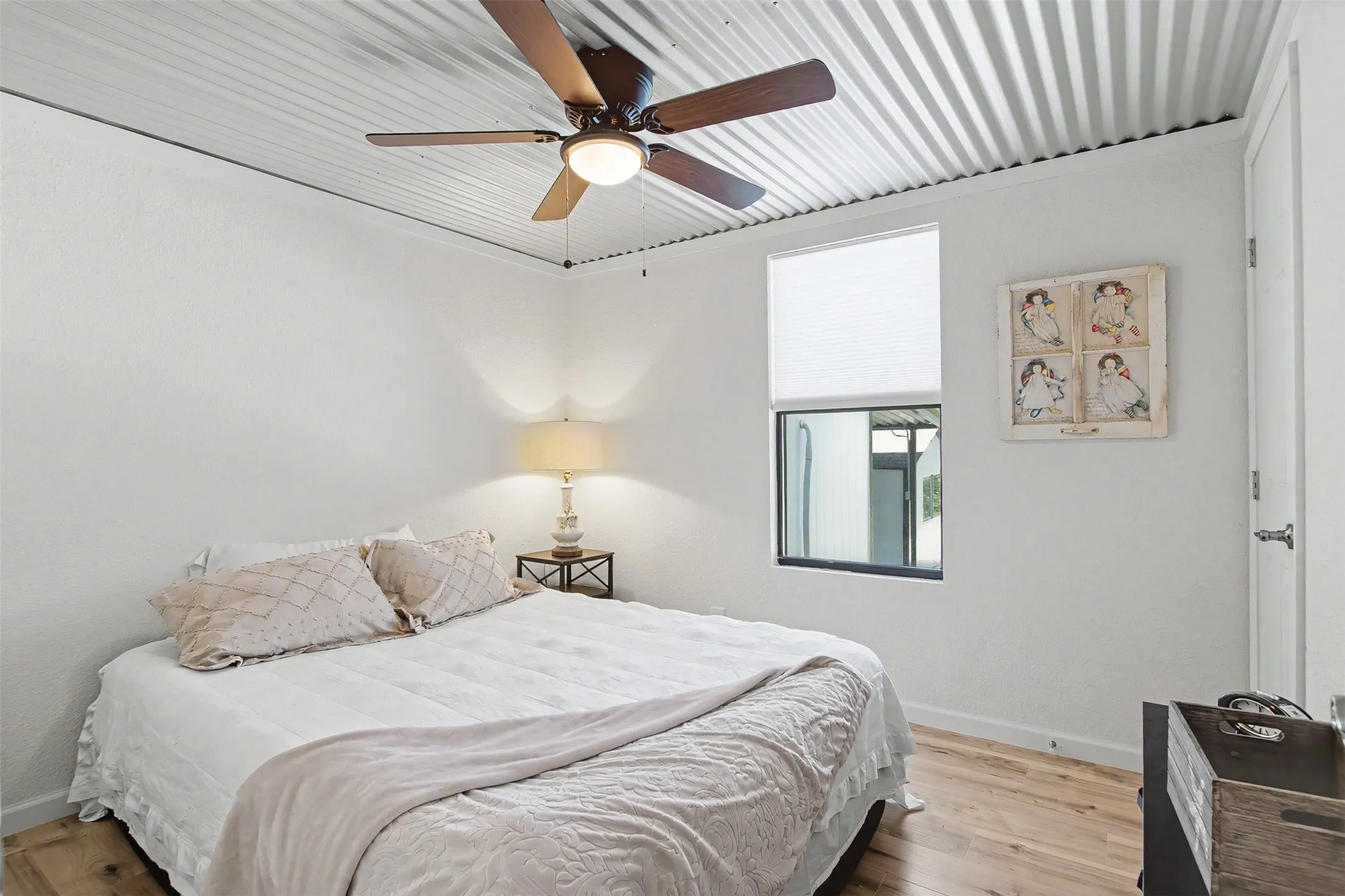 Corrugated metal ceiling featuring a ceiling fan with integrated lighting