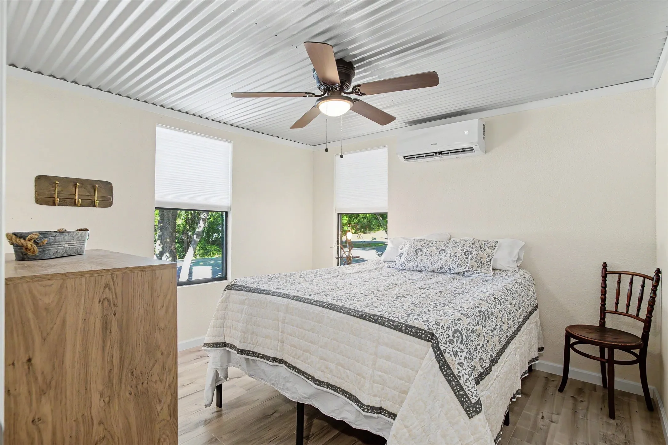 Bedroom featuring a corrugated metal ceiling, wood-finish flooring, and white walls