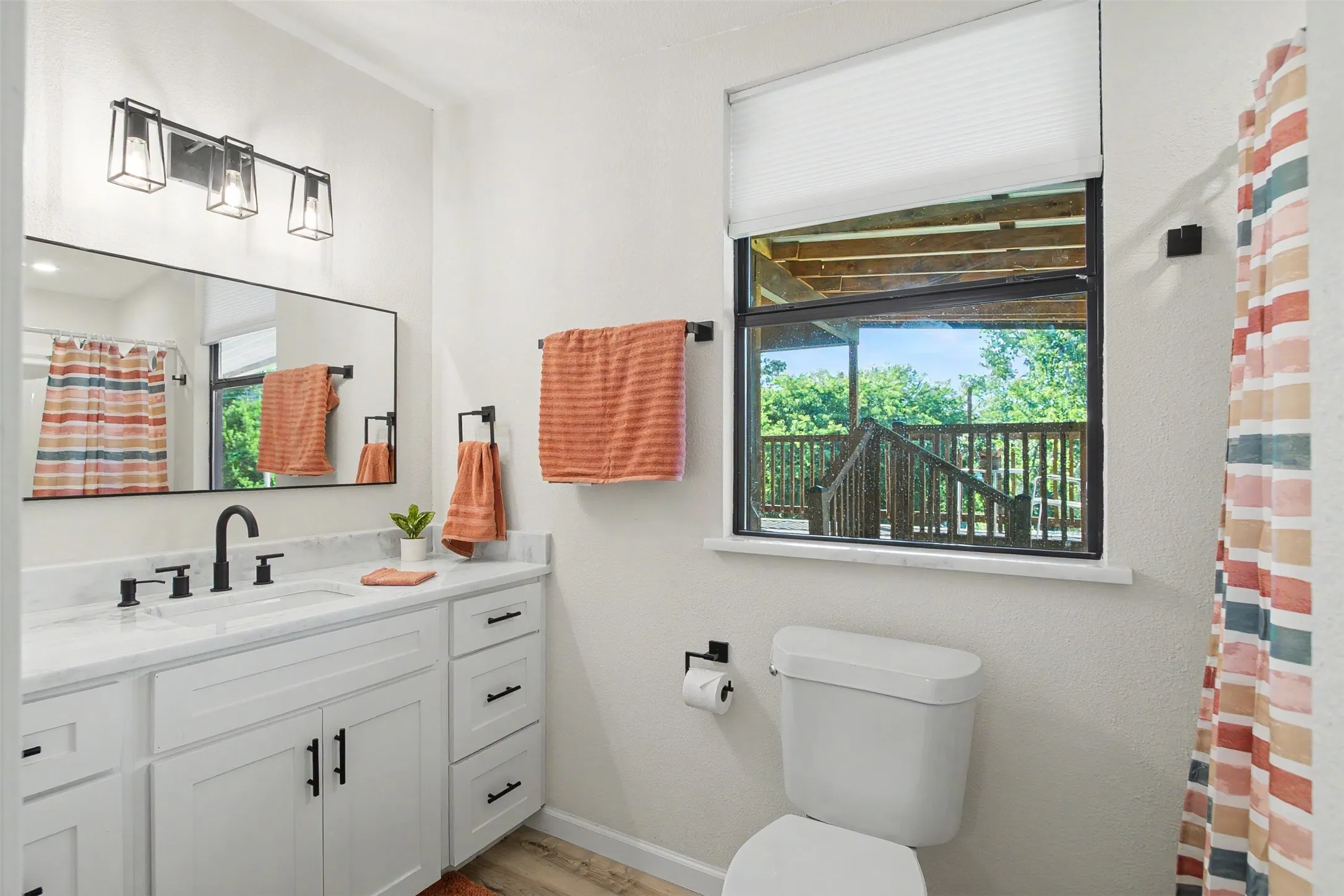 Bathroom featuring a white vanity with dual sinks, quartz-finish countertop, and matte black fixtures