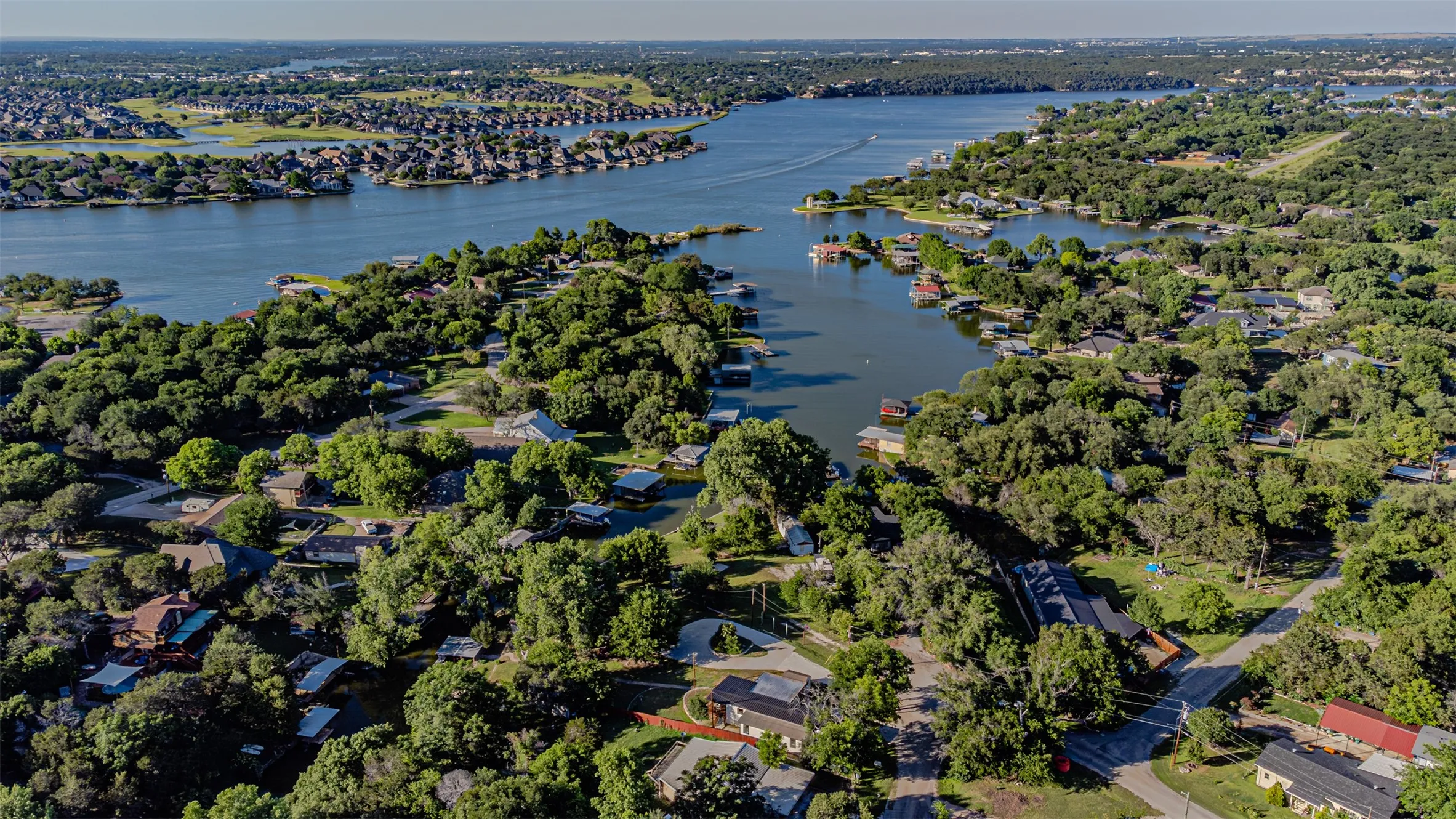 Aerial panorama showcasing a residential community with abundant mature trees and direct water access