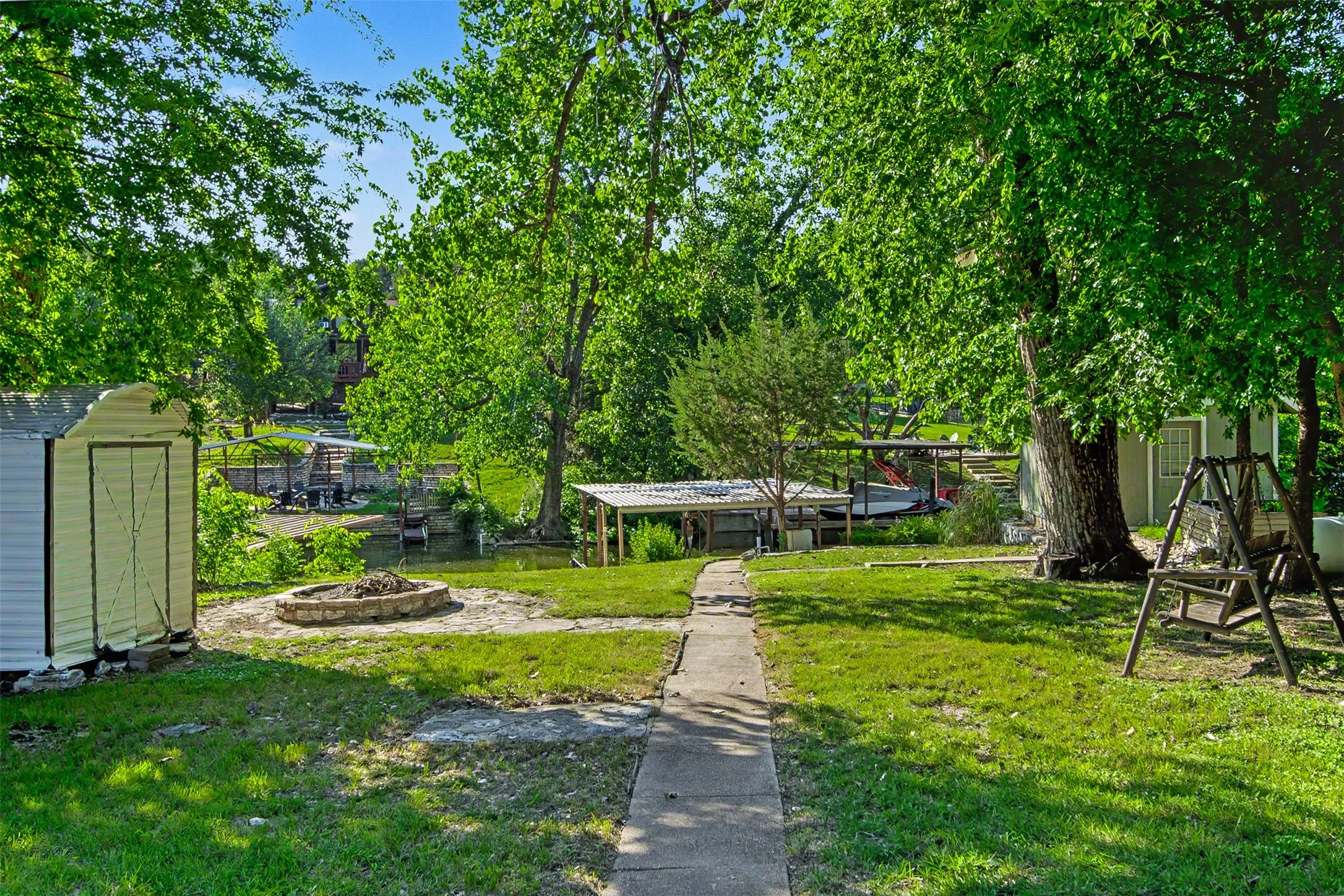 Expansive green lawn with mature trees and a concrete pathway