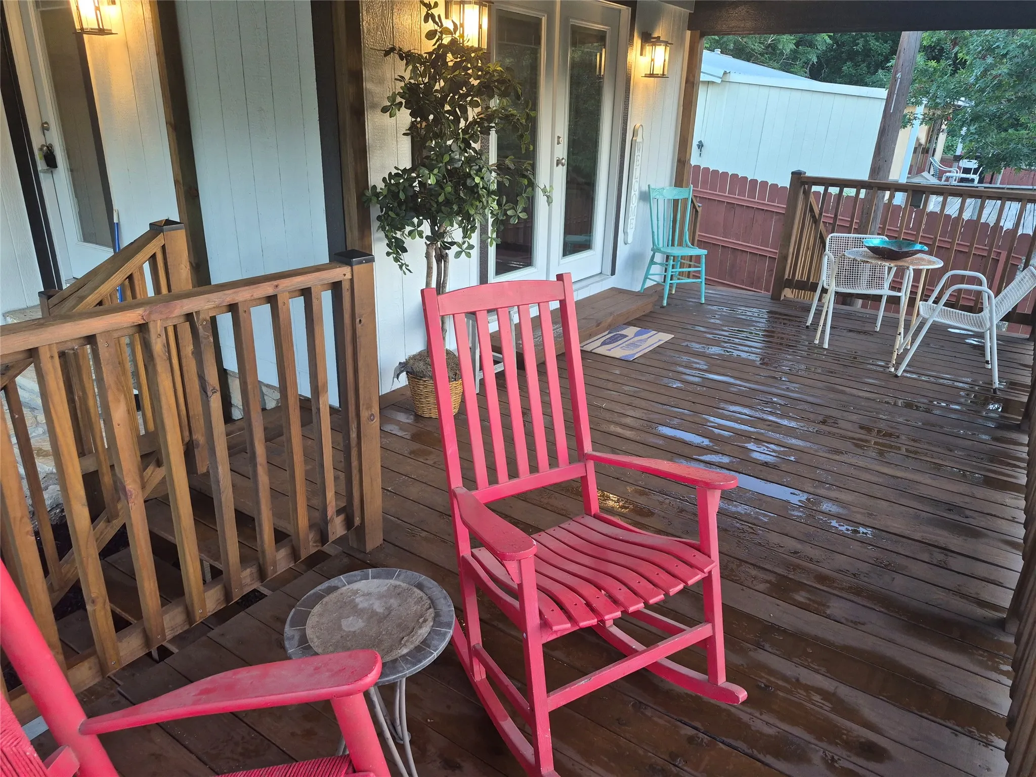 Wood-finish decking with railings and stairs, featuring a covered porch with exposed wood beams and a corrugated metal roof